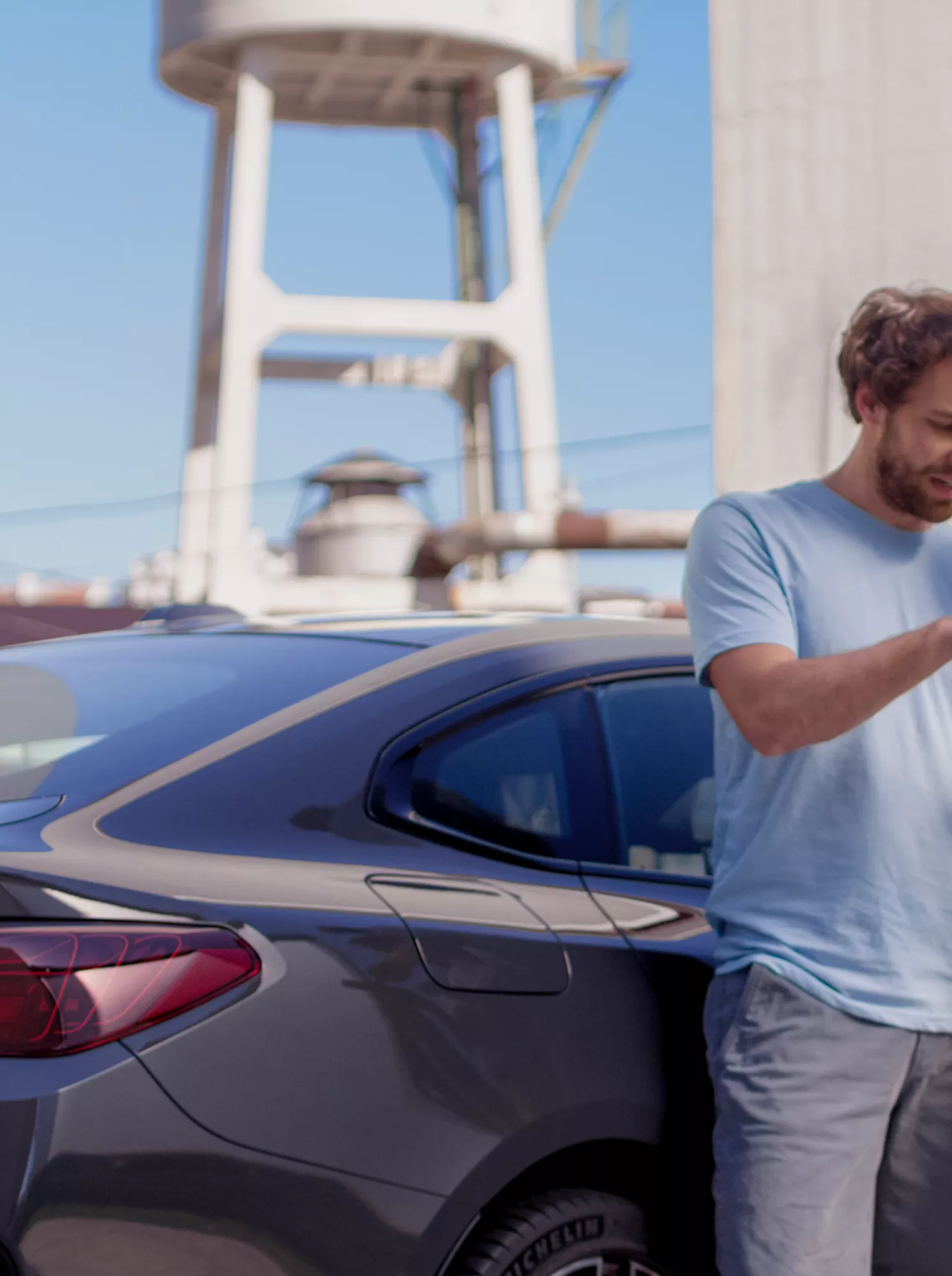  Homme et femme utilisent un smartphone ensemble à côté d’une BMW garée.
