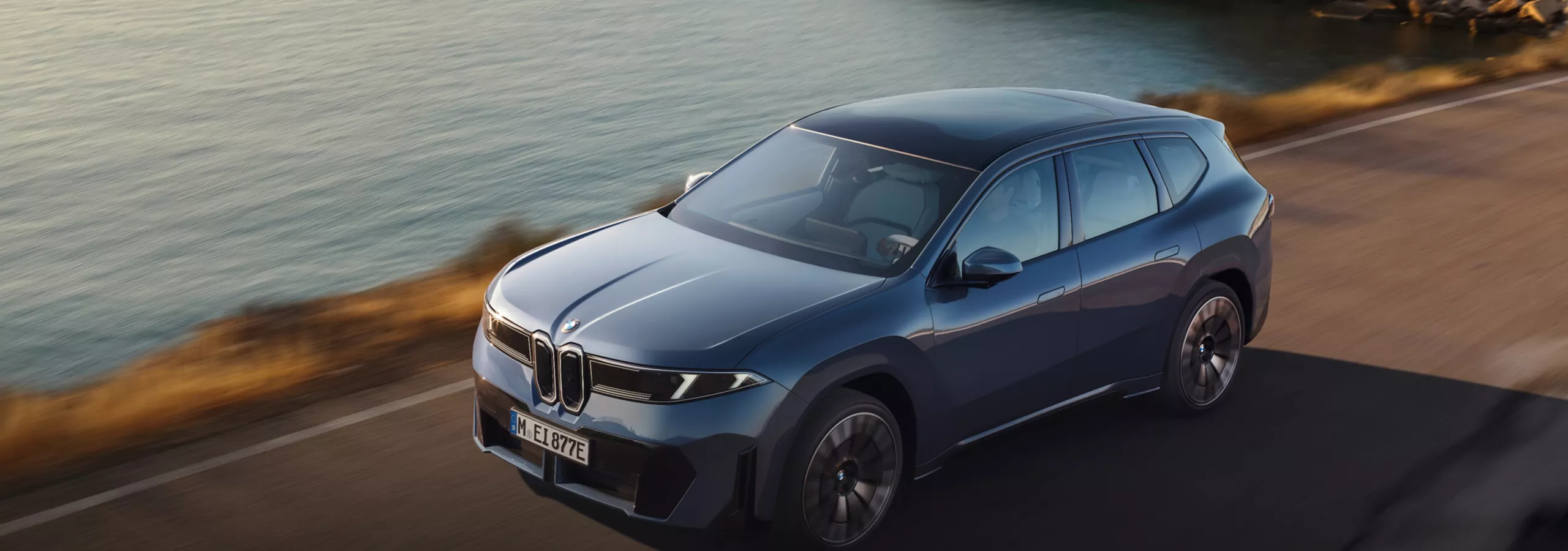 BMW iX3 a andar na estrada junto ao mar