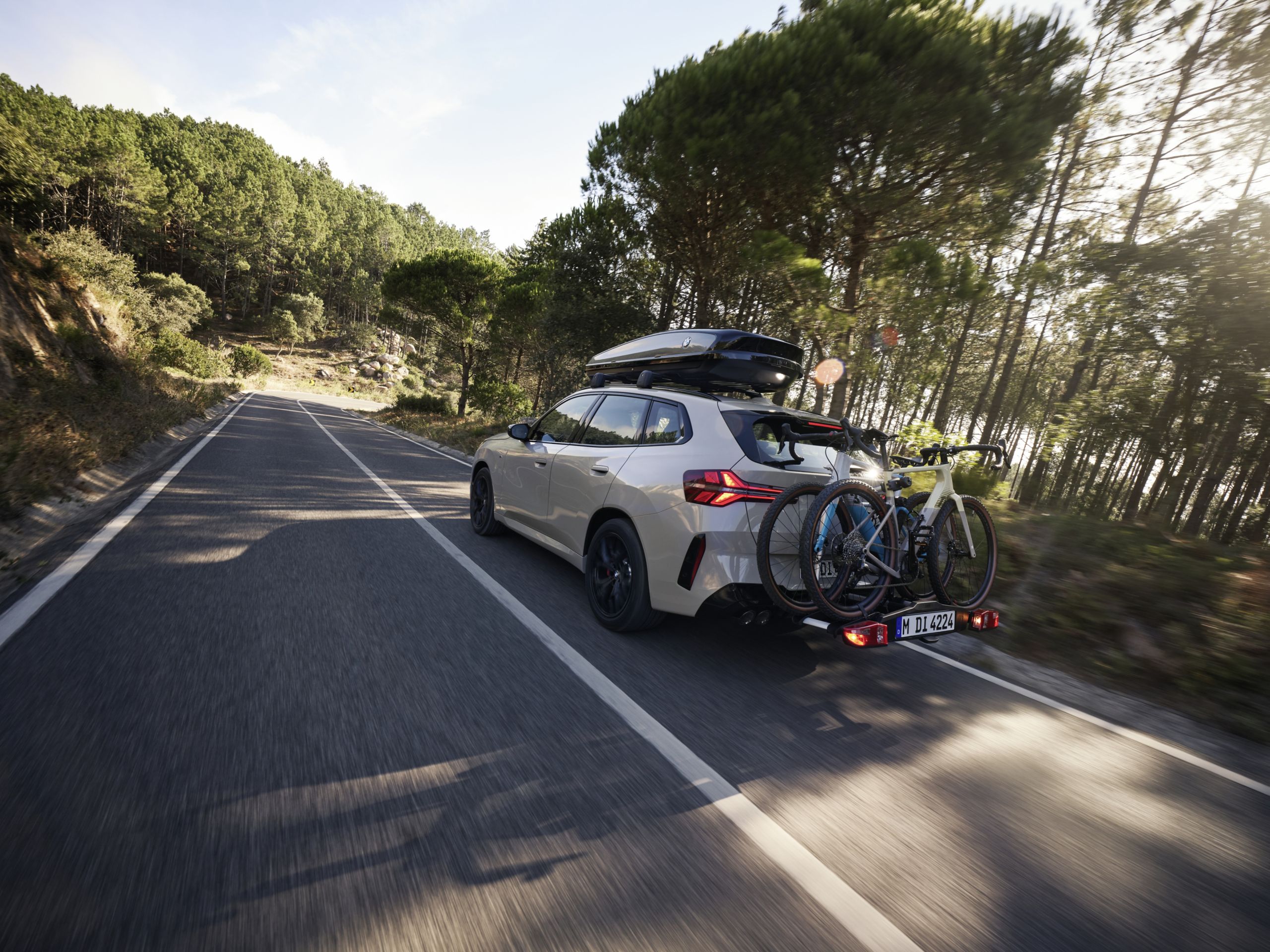 BMW X3 M50 xDrive equipado com suporte para bicicletas e caixa de tejadilho a circular na estrada