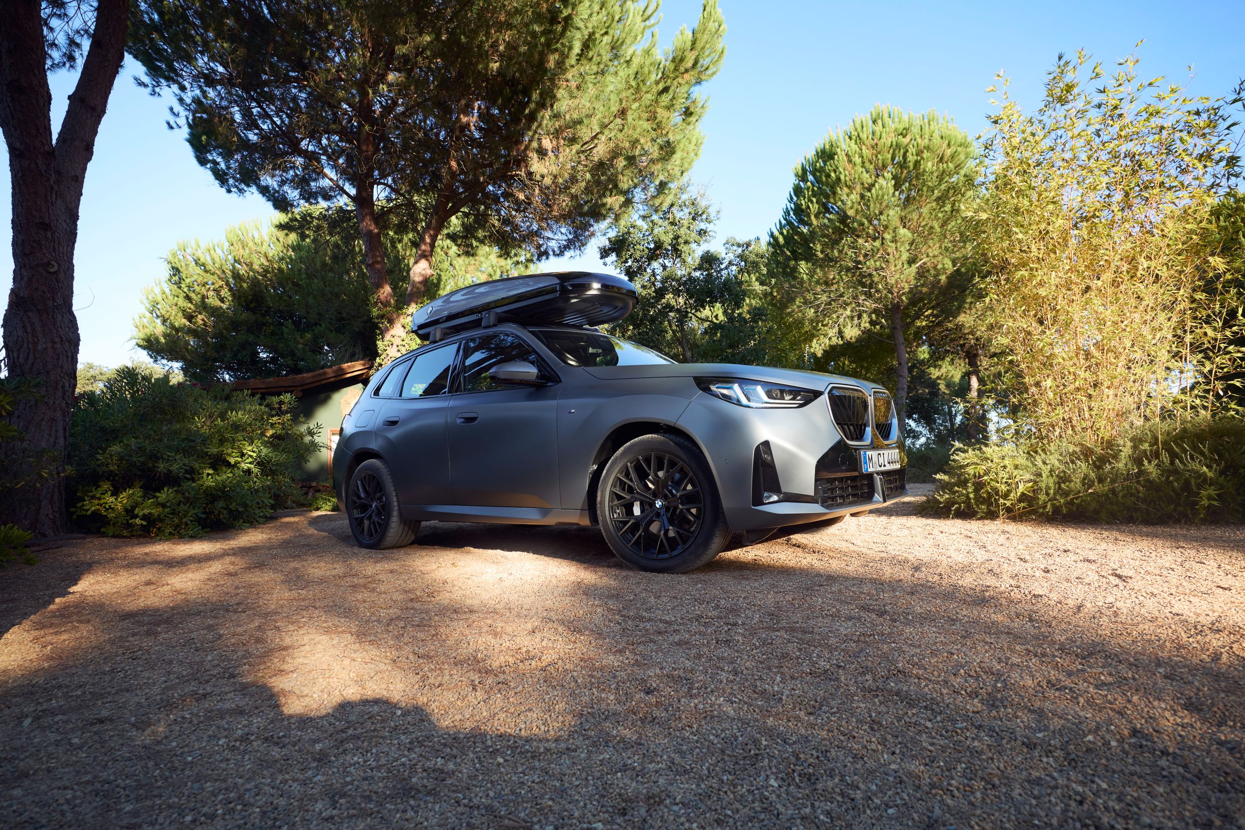BMW X3 20 xDrive com caixa de tejadilho estacionado ao lado de uma árvore