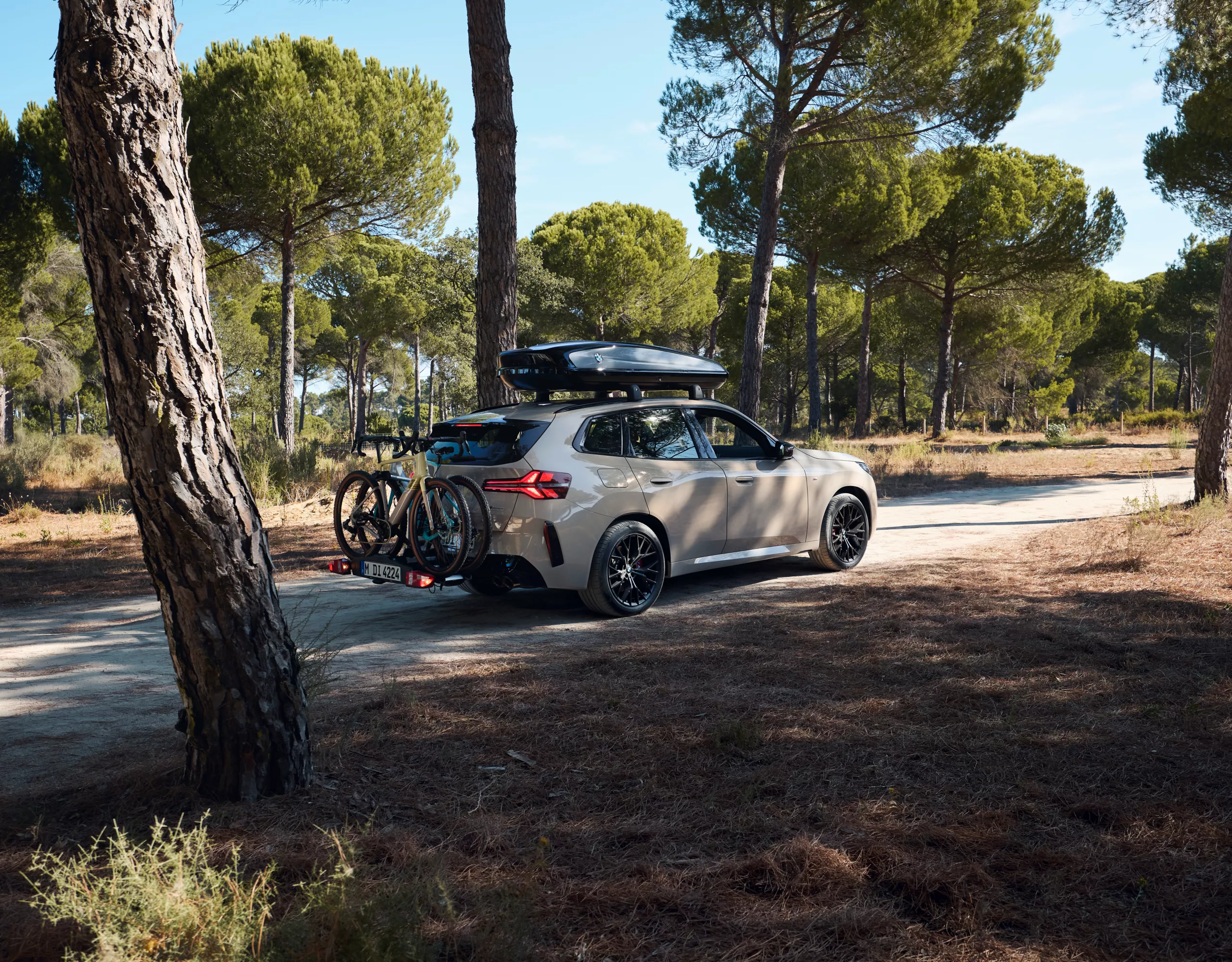 BMW X3 M50 xDrive equipado com suporte para bicicletas e caixa de tejadilho estacionado no meio da natureza.