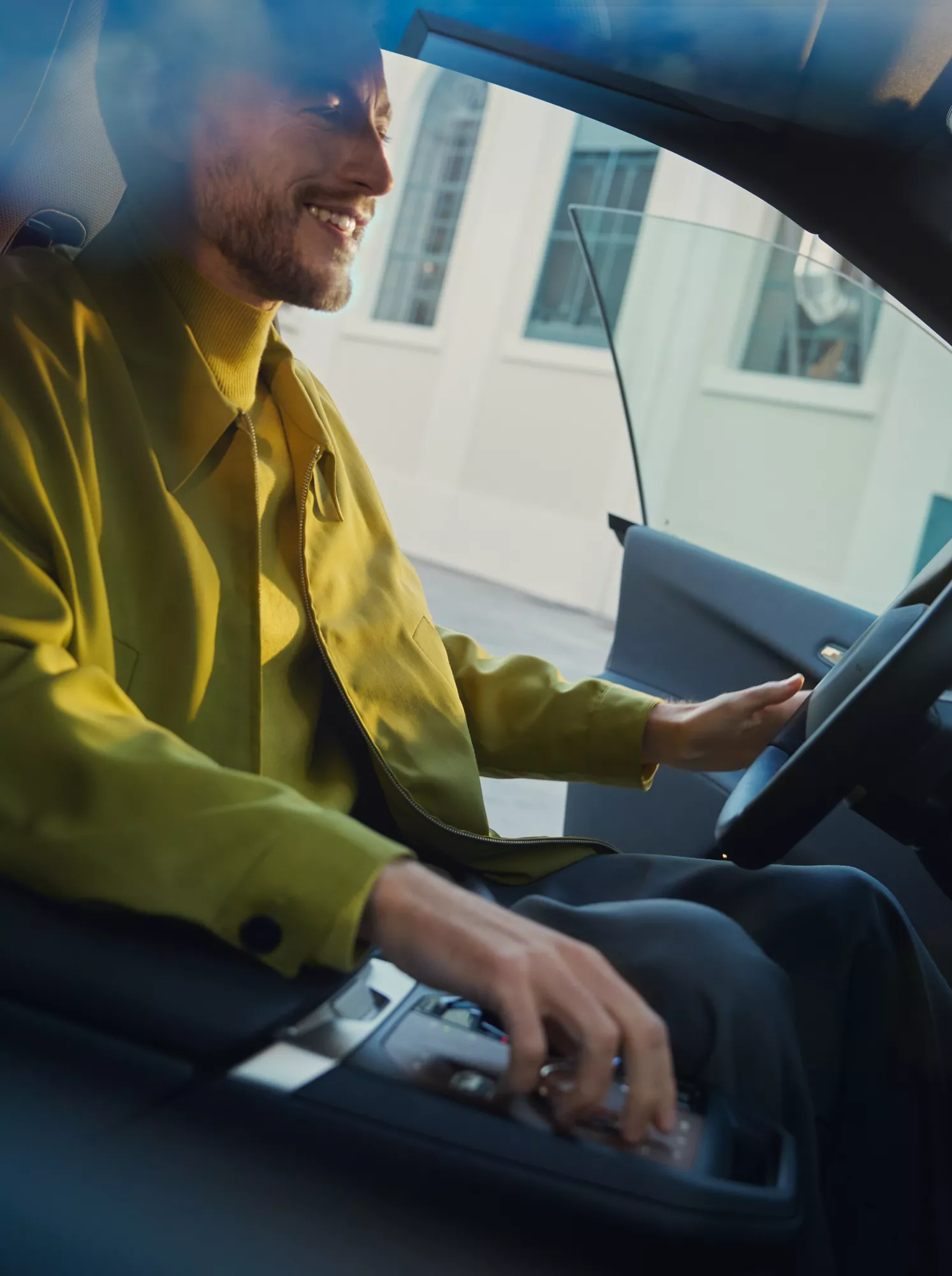 Ansicht eines BMW Innenraums mit Lenkrad, Mittelkonsole und einer Hand an den Bedienelementen.