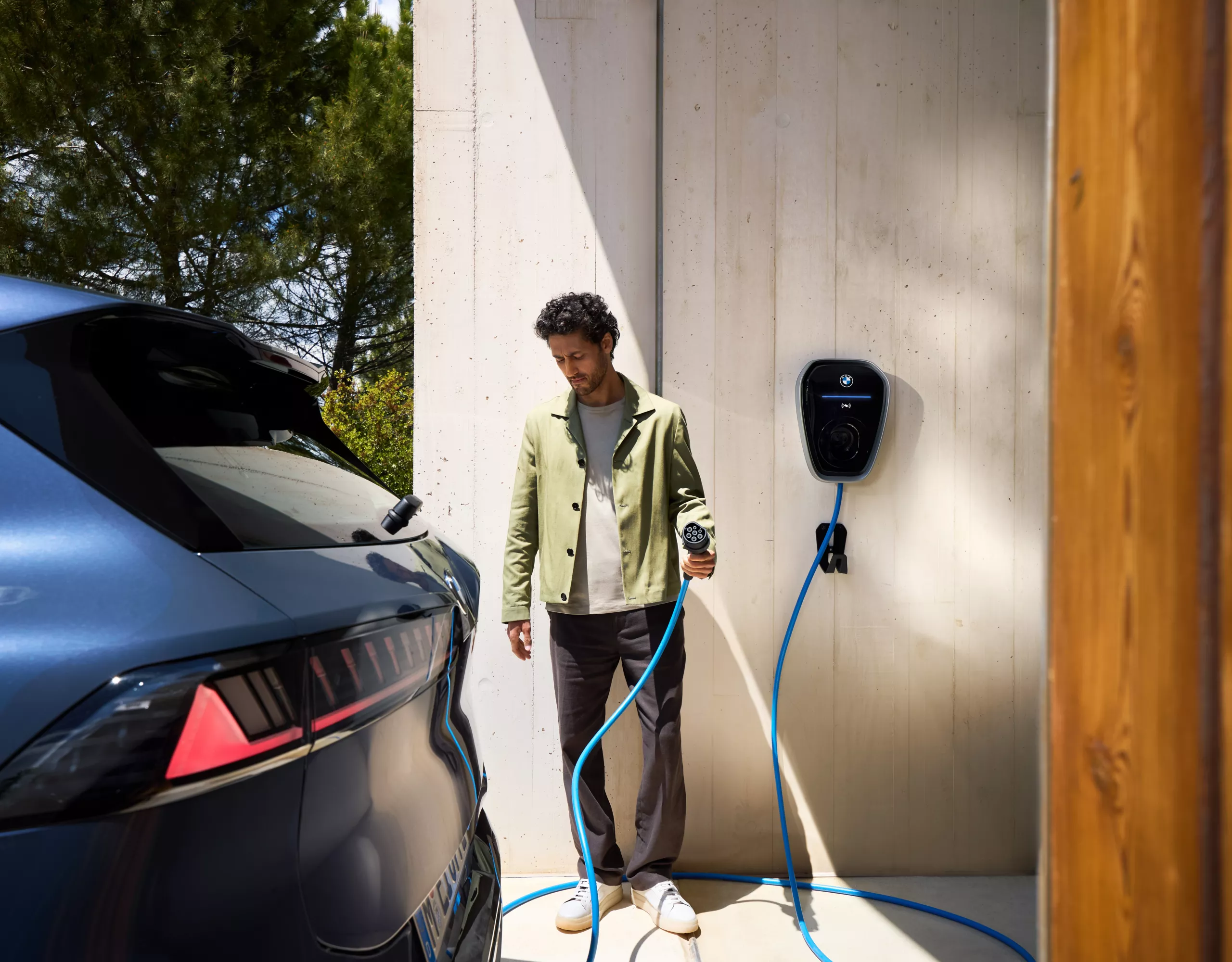 Une personne munie d’un câble de recharge de wallbox se dirige vers une BMW