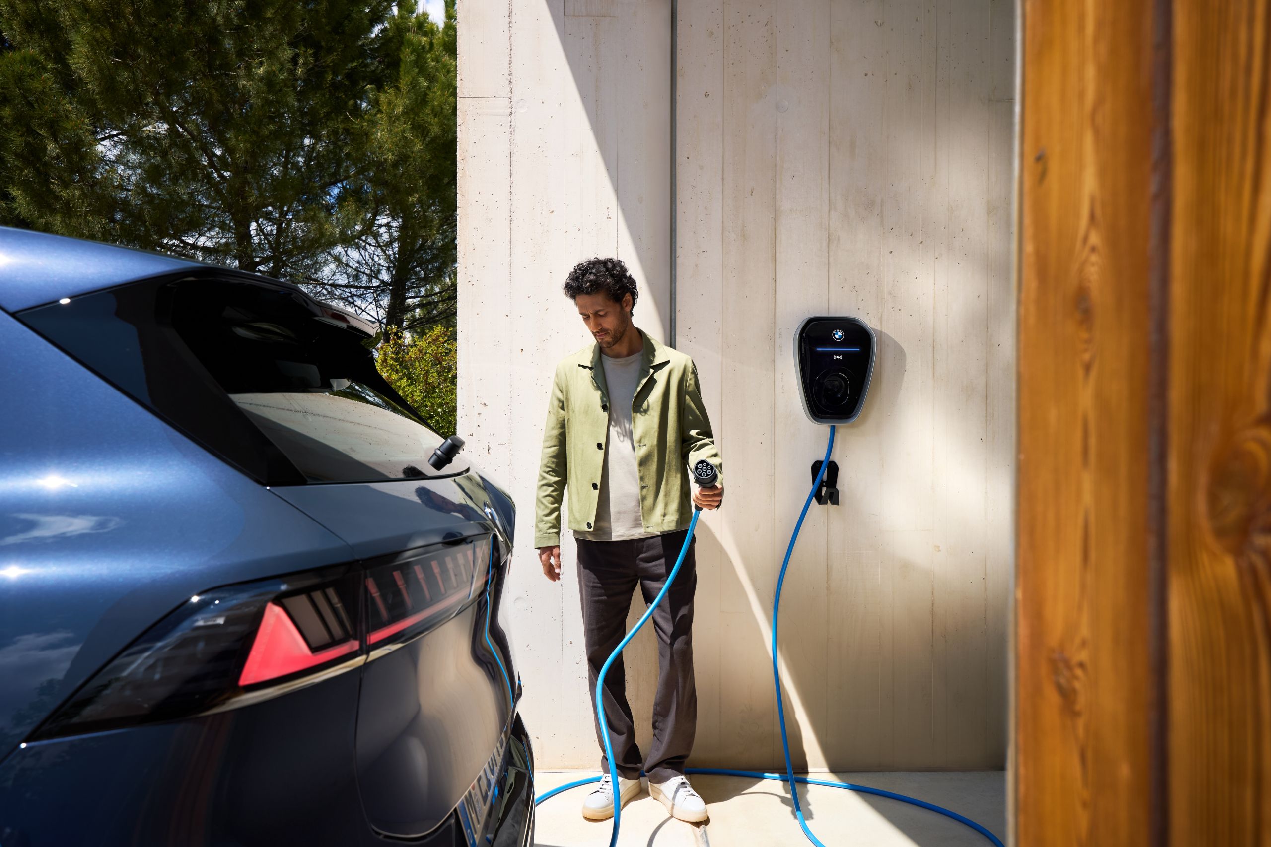 Une personne munie d’un câble de recharge de wallbox se dirige vers une BMW