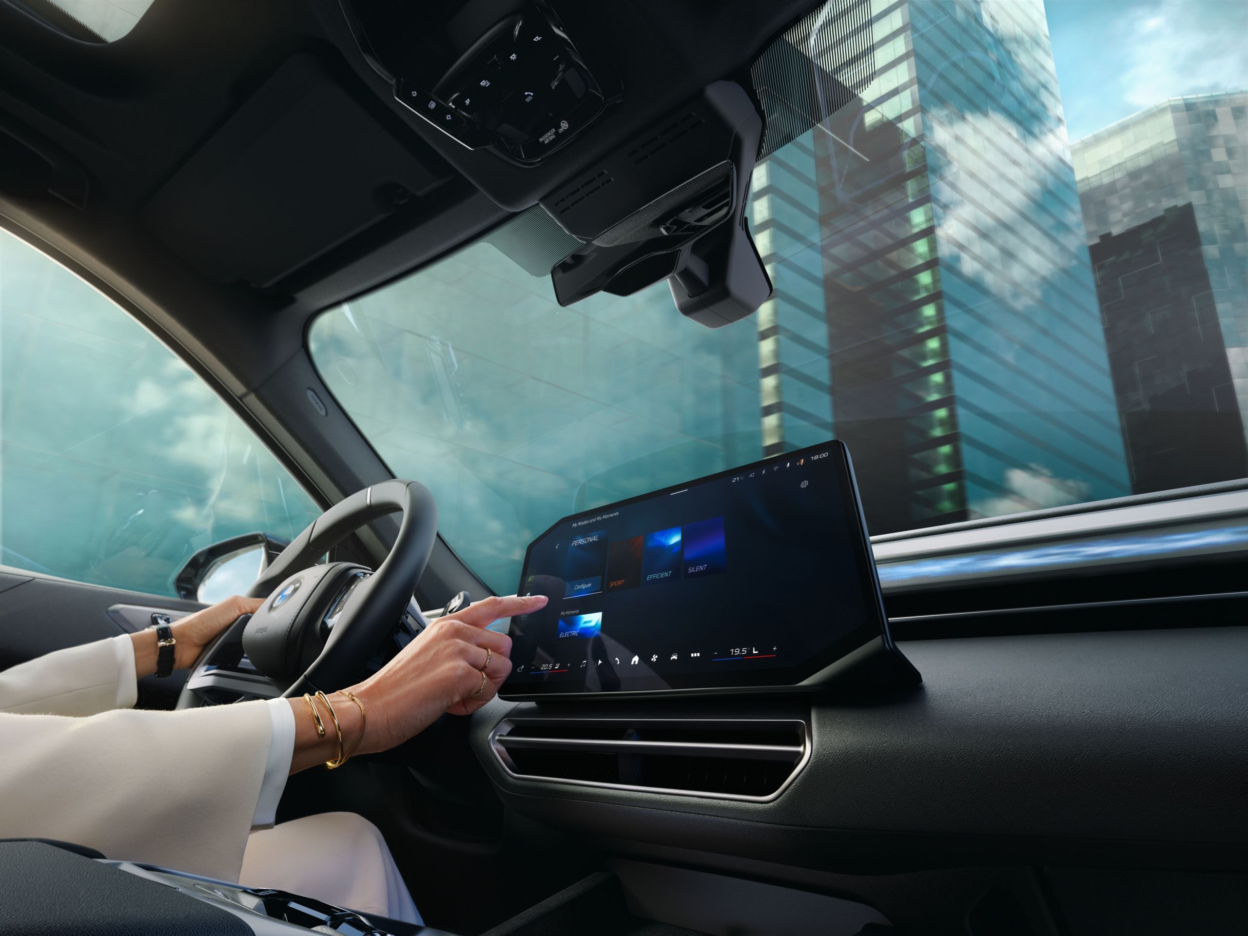 A hand touches the central screen in a BMW