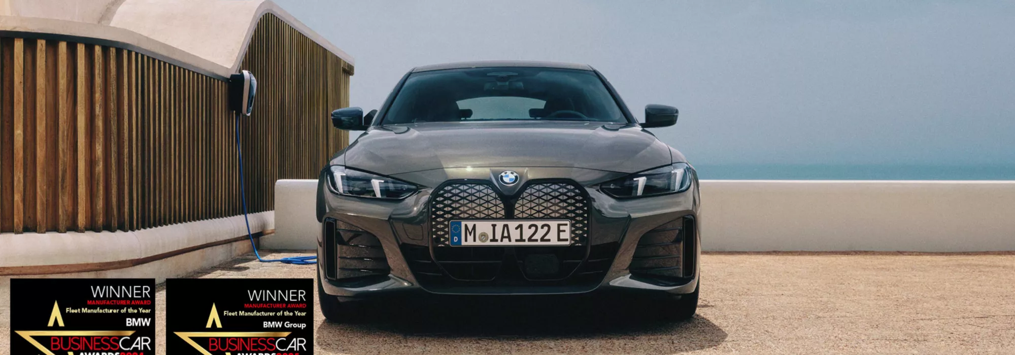 BMW coupe parked in front of a wooden architectural wall under clear skies.