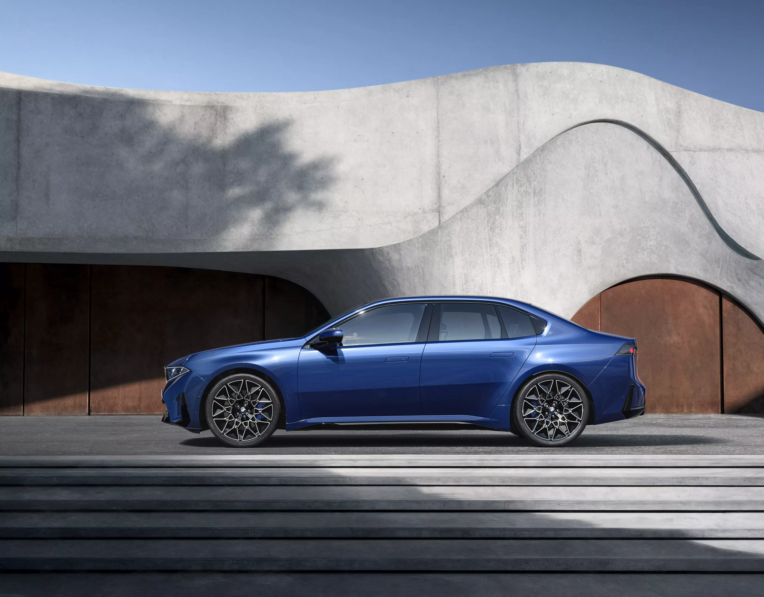 BMW i3 visto de lado, estacionado junto a um edifício de betão com escadas em primeiro plano