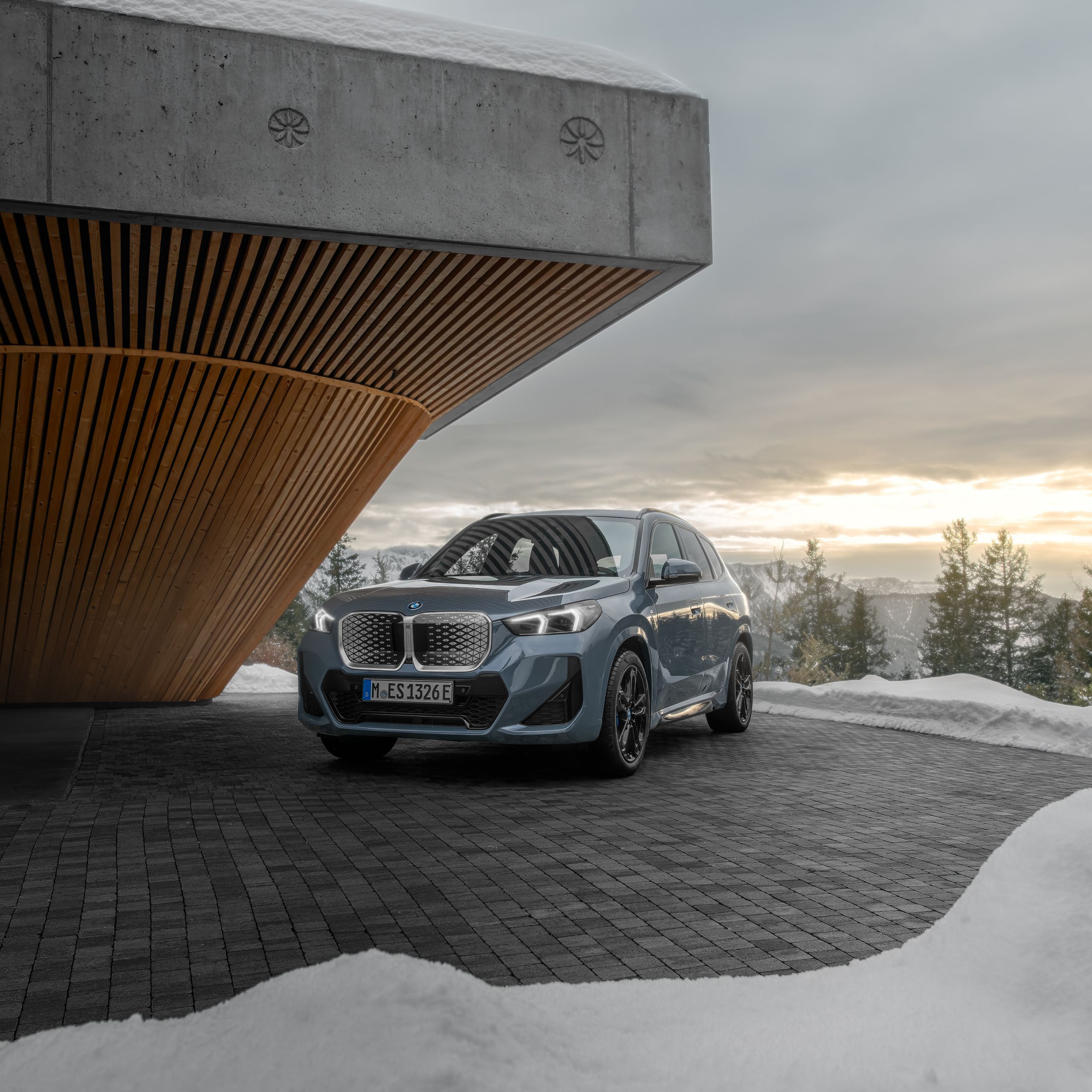 BMW iX1 Frontansicht unter modernem Holzvordach