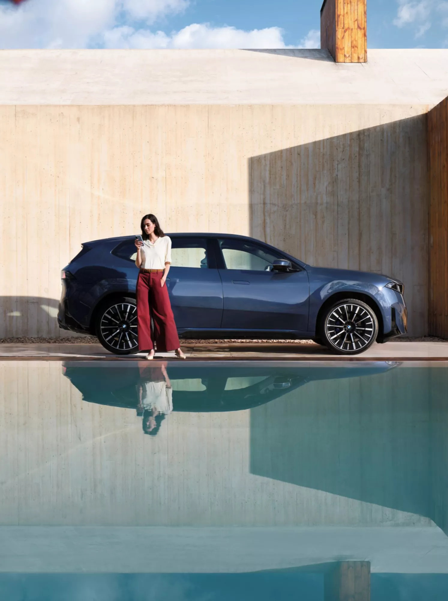 Person standing behind a BMW holding a smartphone
