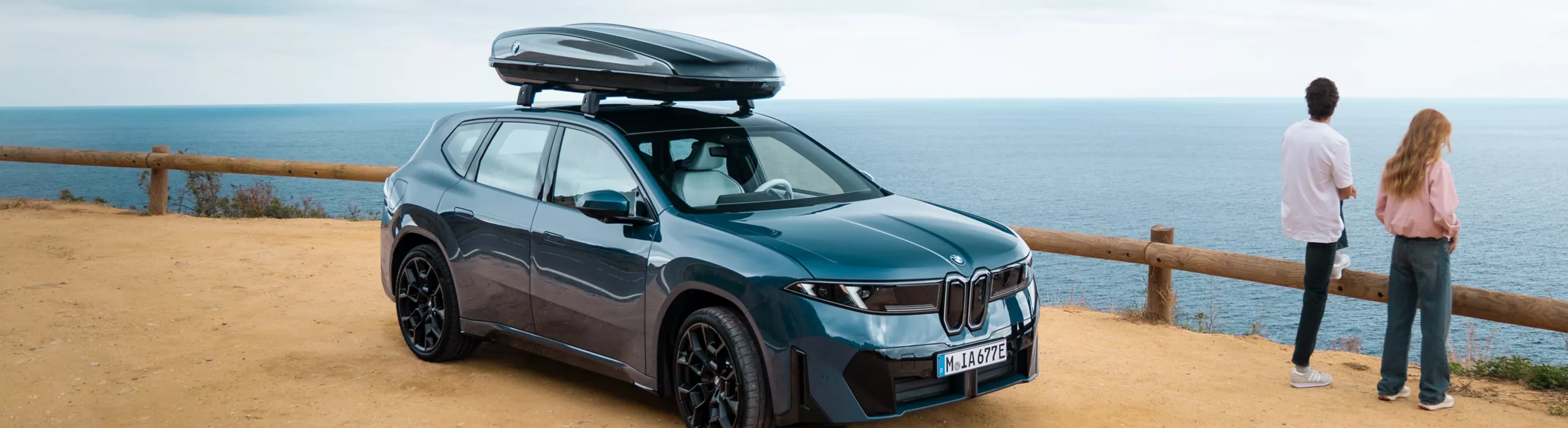 BMW mit Fahrradträger am Heck in einer Frühlingslandschaft, während eine Person die Fahrräder vorbereitet