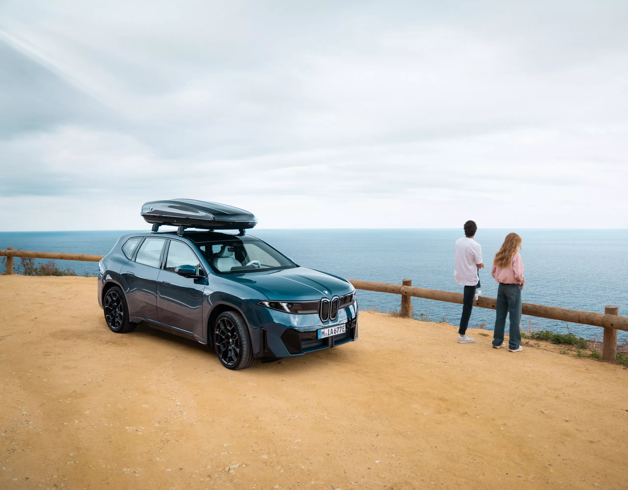 BMW mit Fahrradträger am Heck in einer Frühlingslandschaft, während eine Person die Fahrräder vorbereitet