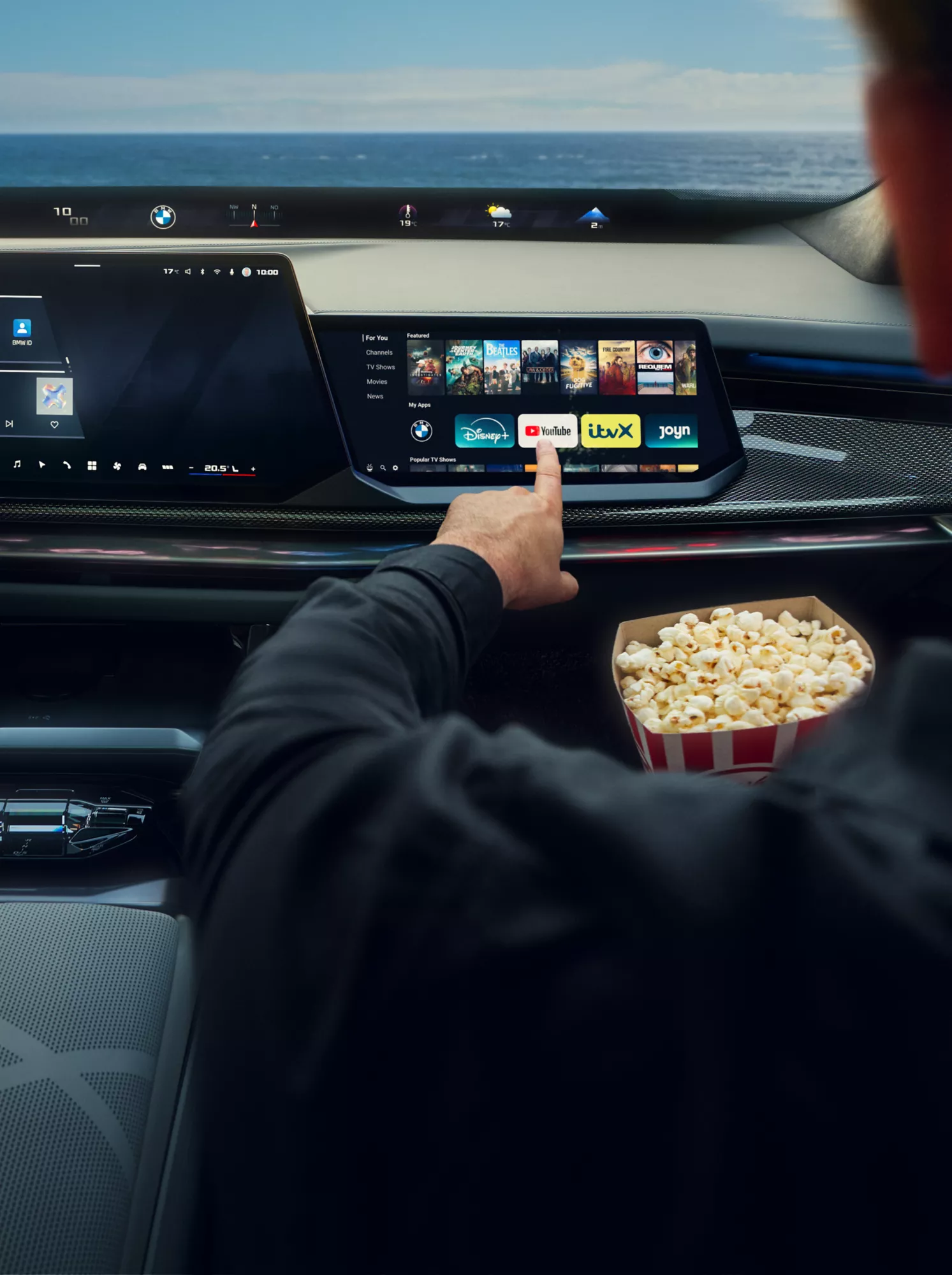 A woman is watching Disney+ streaming inside a parked BMW from the driver’s seat