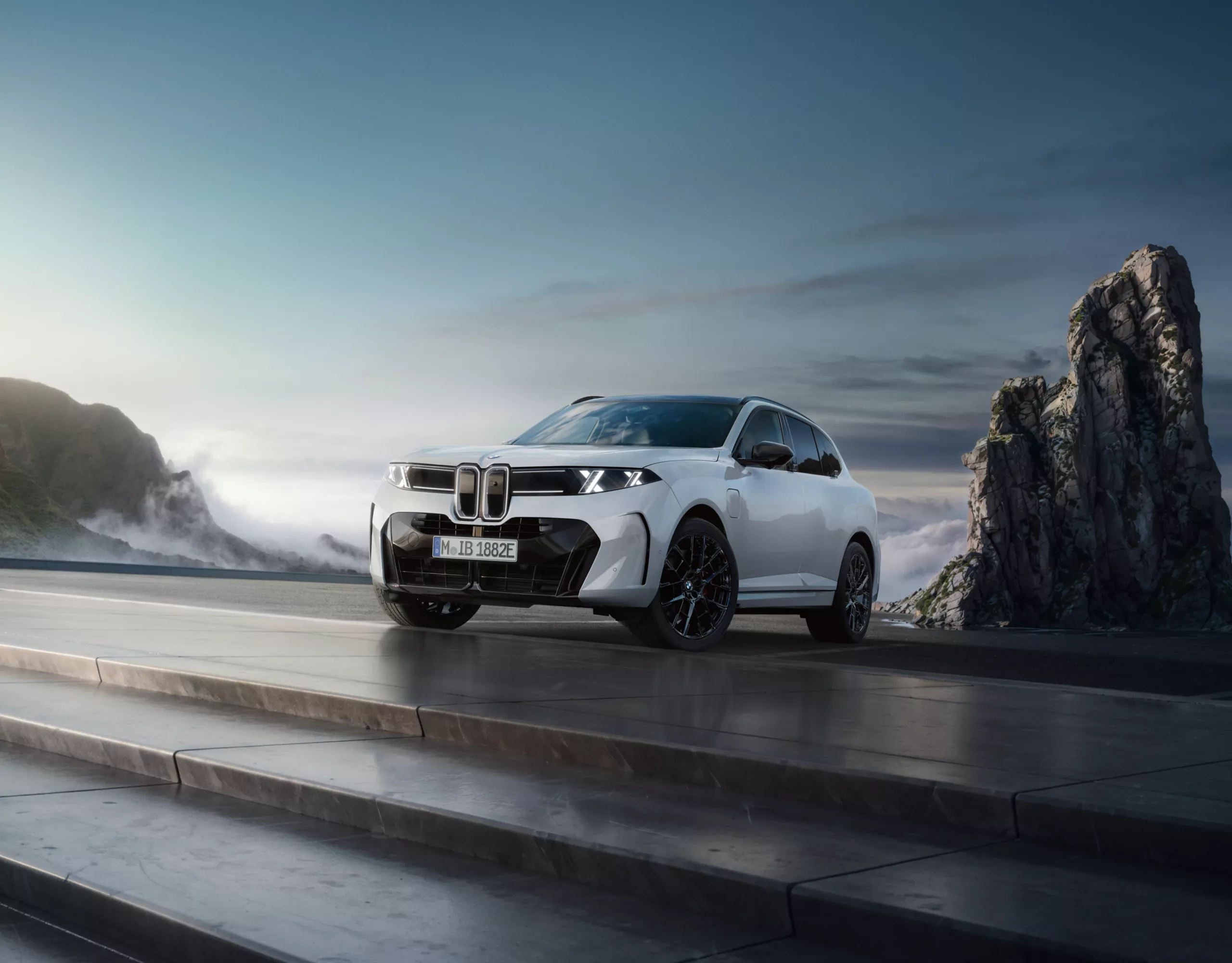 BMW X5 visto de frente e de lado, estacionado junto a uma zona costeira com rochas e céu azul ao fundo