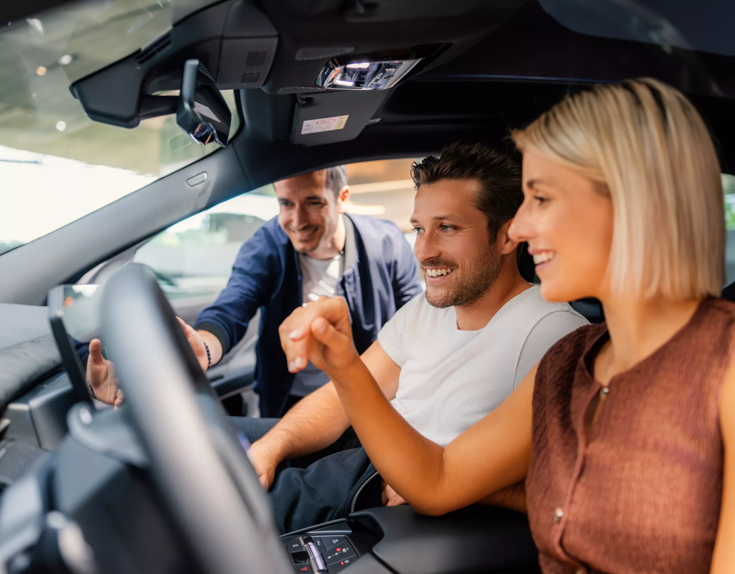 An adult couple sits inside the BMW iX3 while receiving an introduction from a BMW expert.
