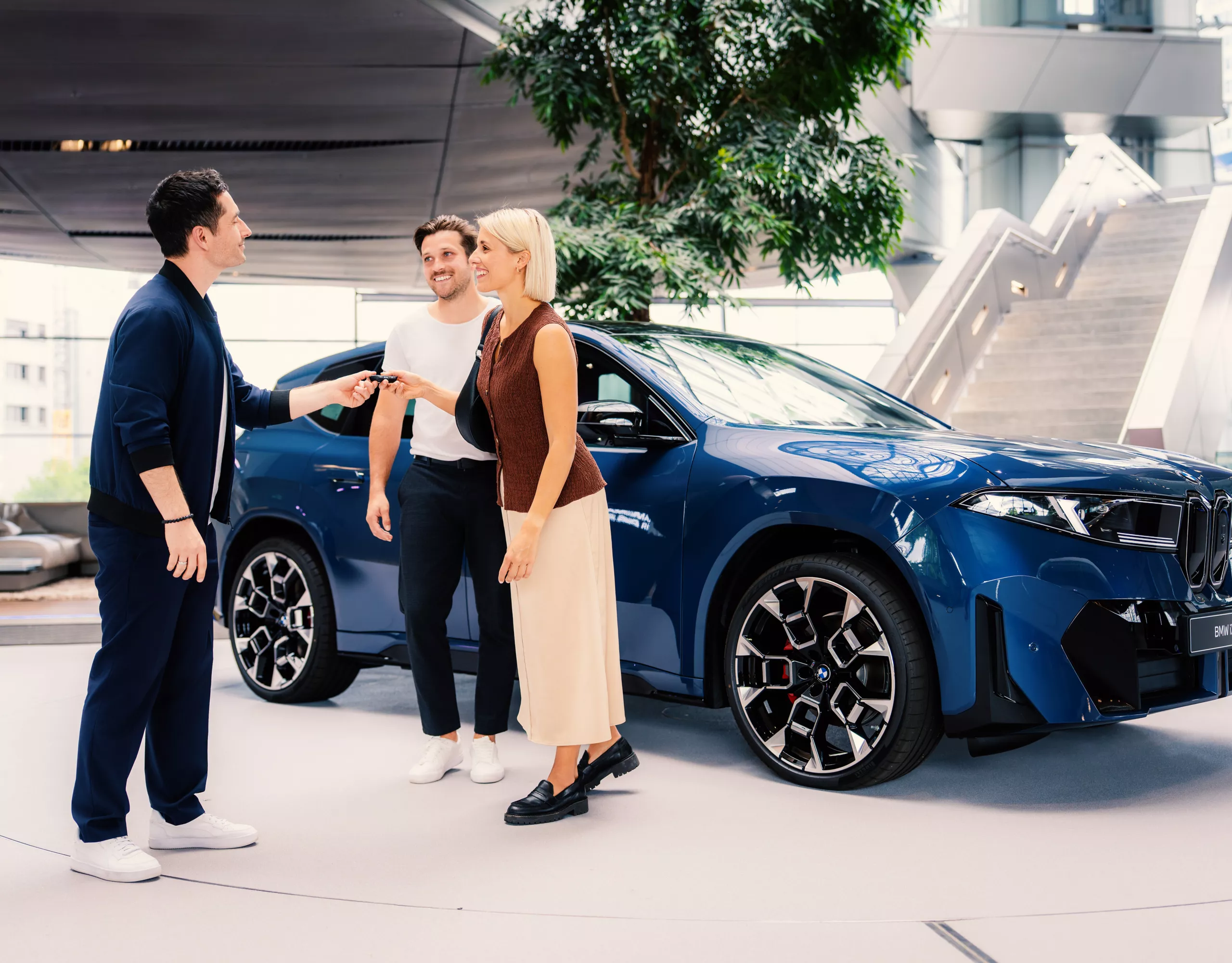 An adult couple receives the keys for the BMW iX3 from a staff member at BMW Welt.