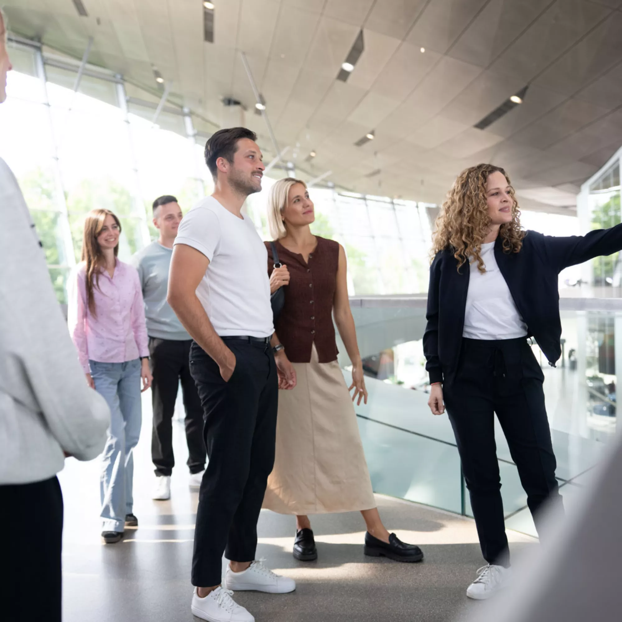 An adult couple follows a guided tour at BMW Welt as an expert explains the exhibition.