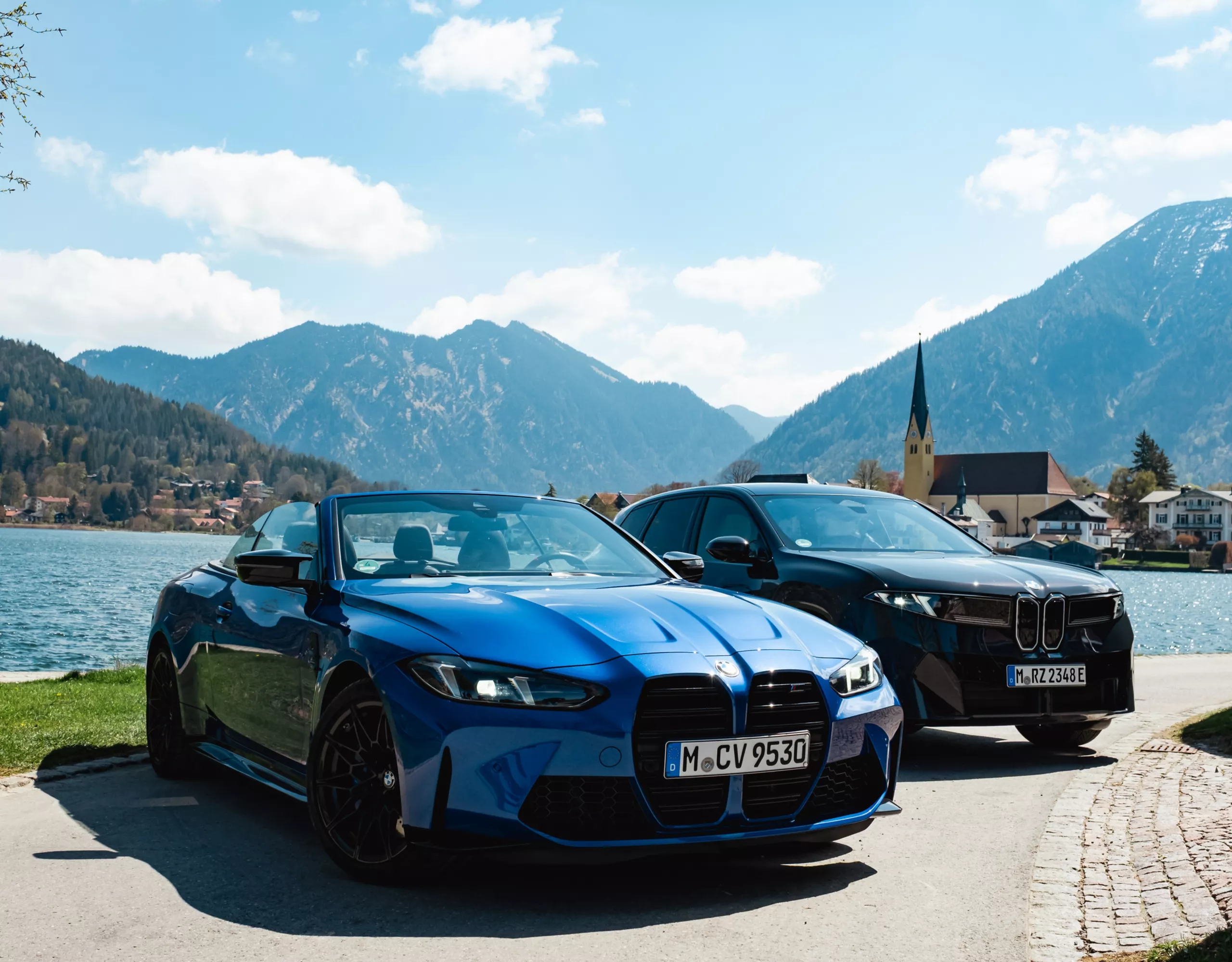 BMW M4 Cabrio und BMW iX3 am Tegernsee vor alpiner Kulisse.