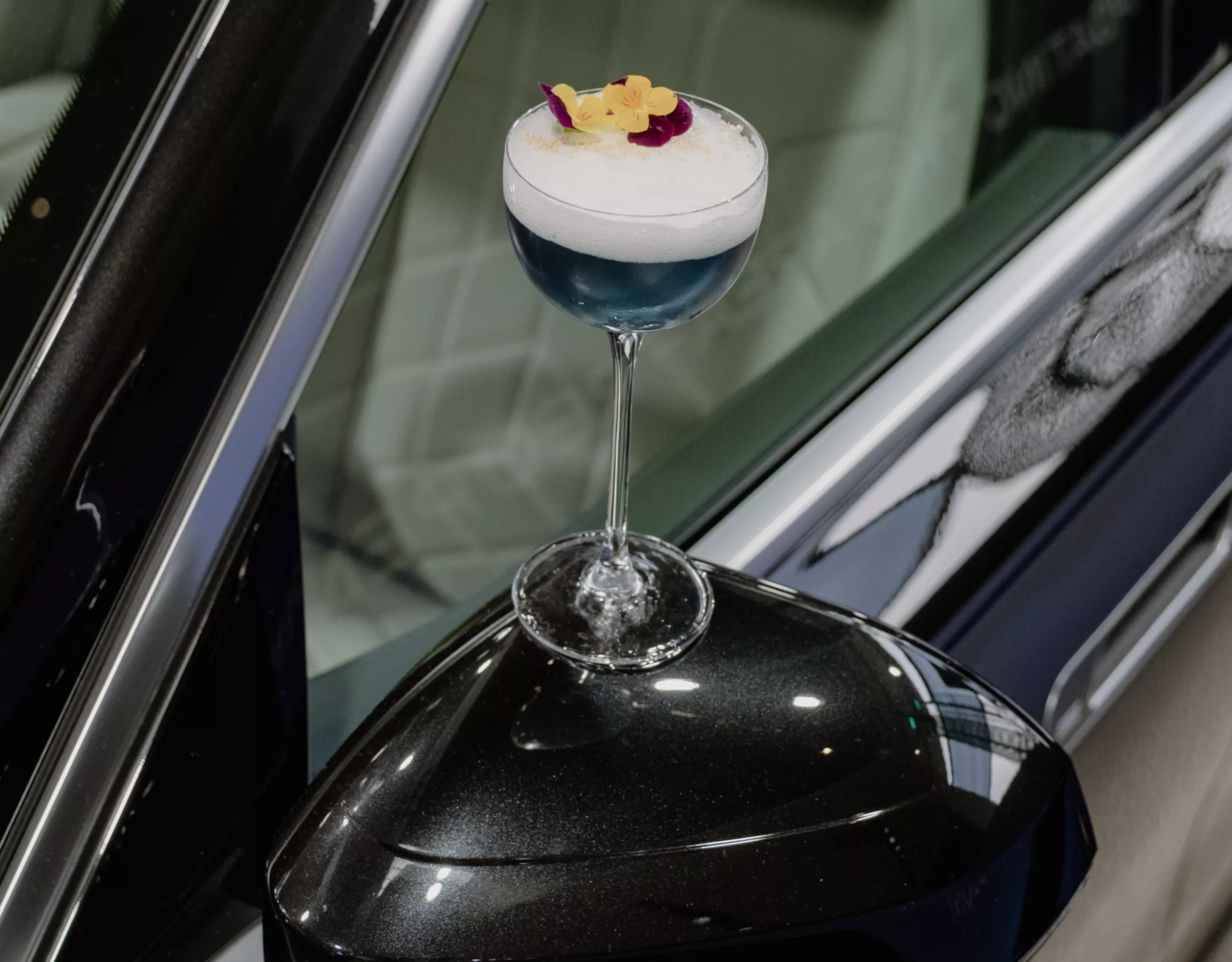 Blue signature cocktail placed on the side mirror of a BMW 7 at BMW Welt.