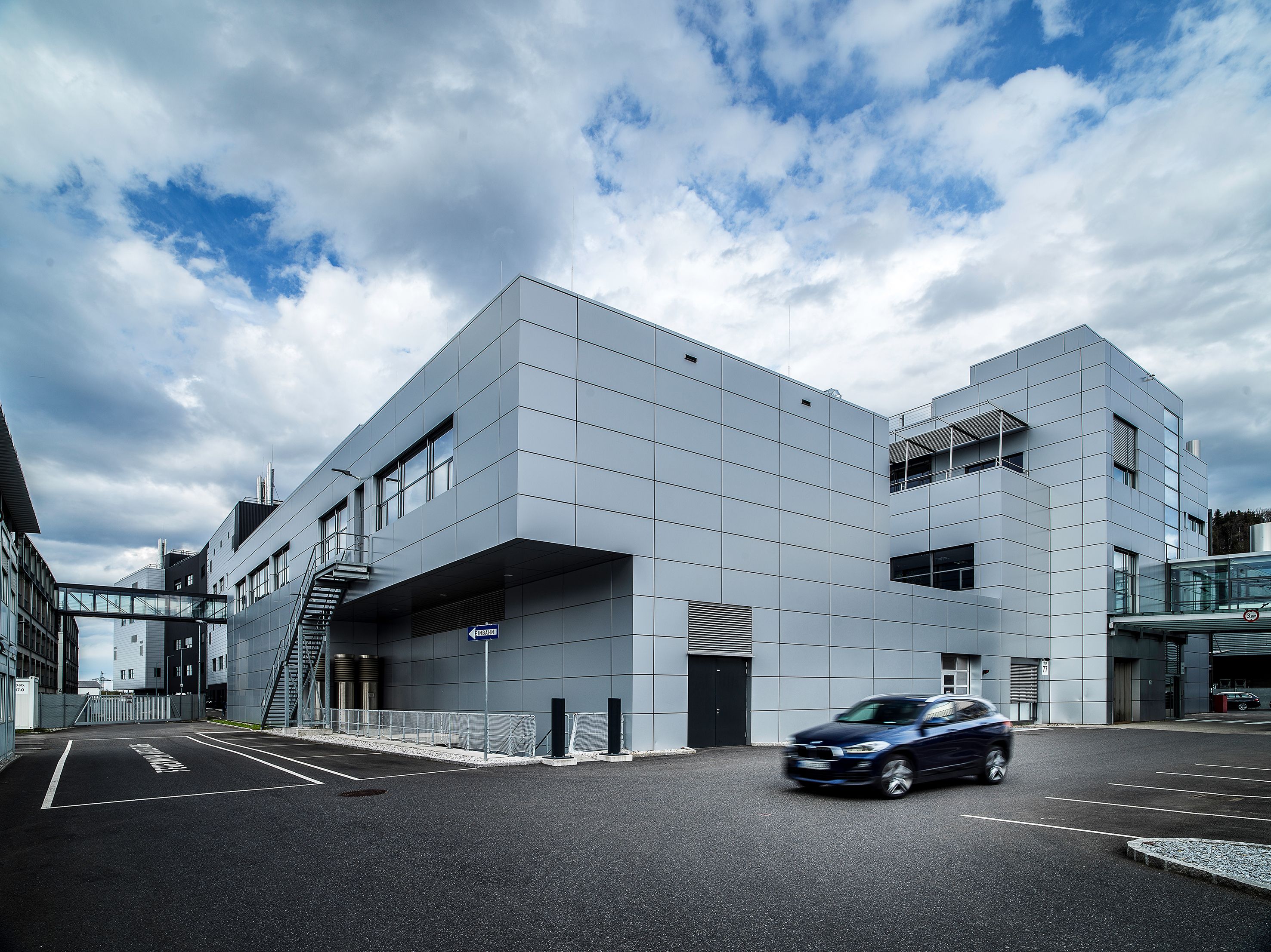 Ein dunkelblauer BMW 2er Active Tourer fährt über das Industriegelände des BMW Group Werk Steyr. 