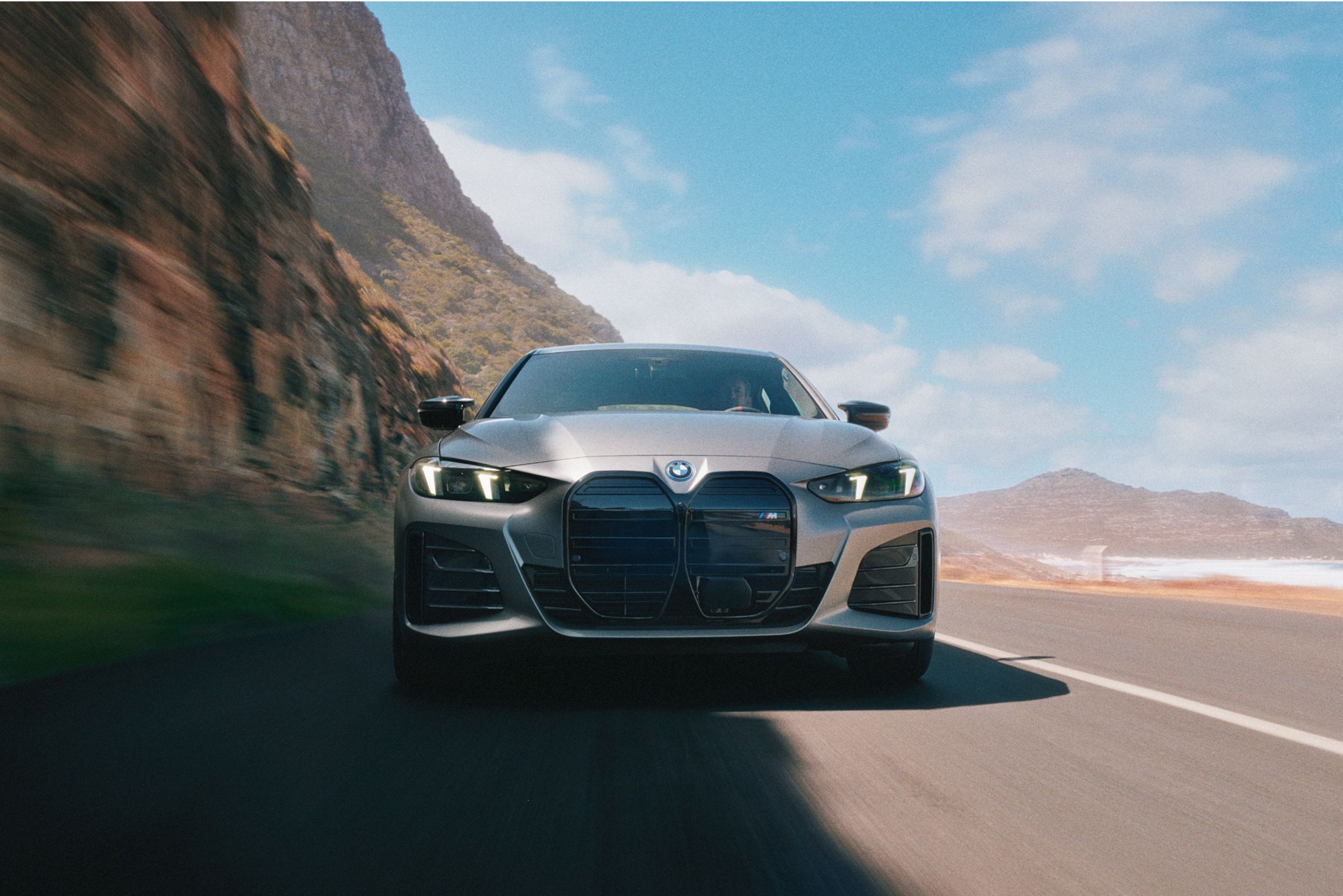 A frontal shot of the BMW i4 as it drives down a desert canyon highway