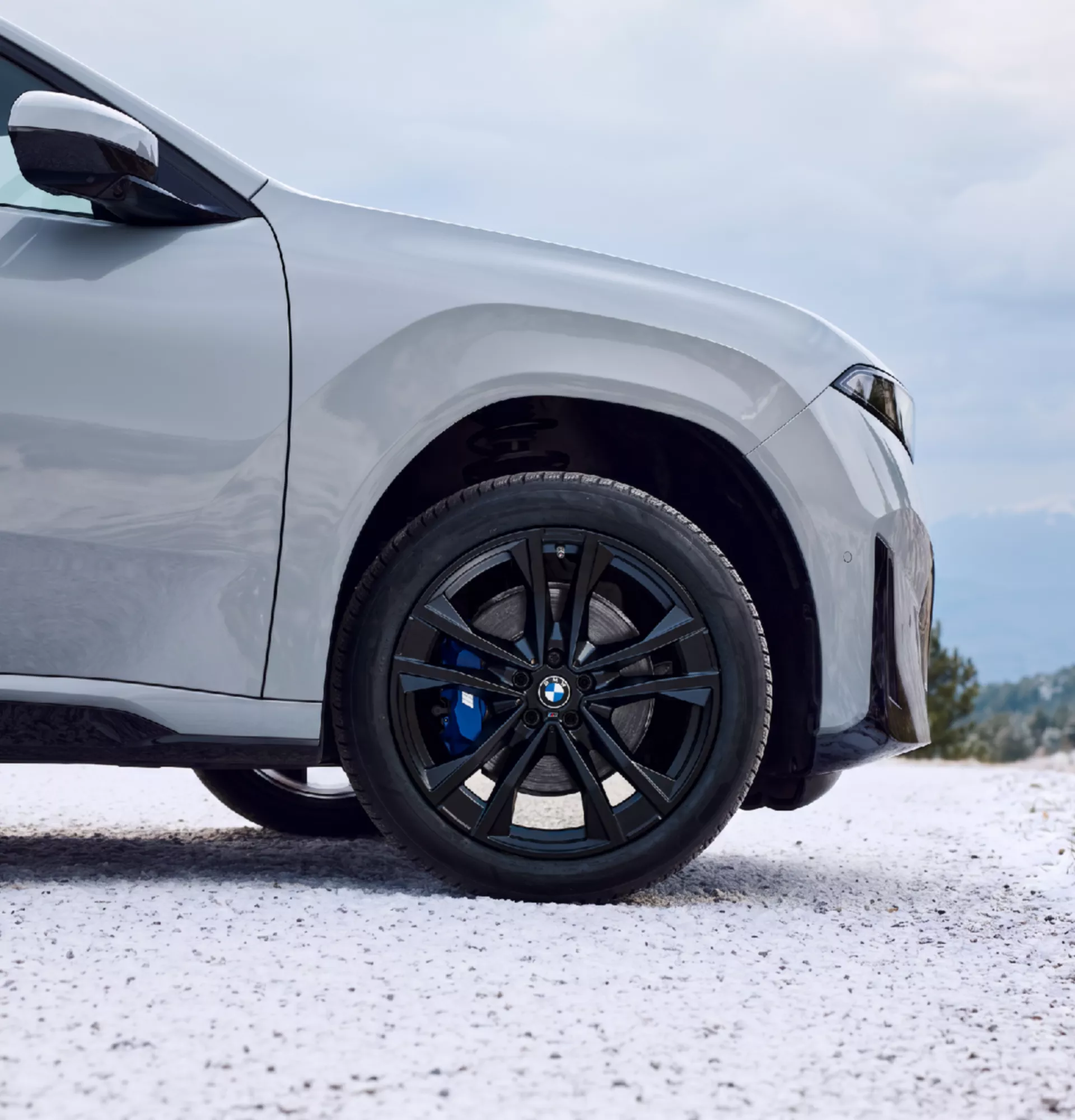 Light alloy wheel with blue M sport brake caliper BMW, front wheel on gravel road