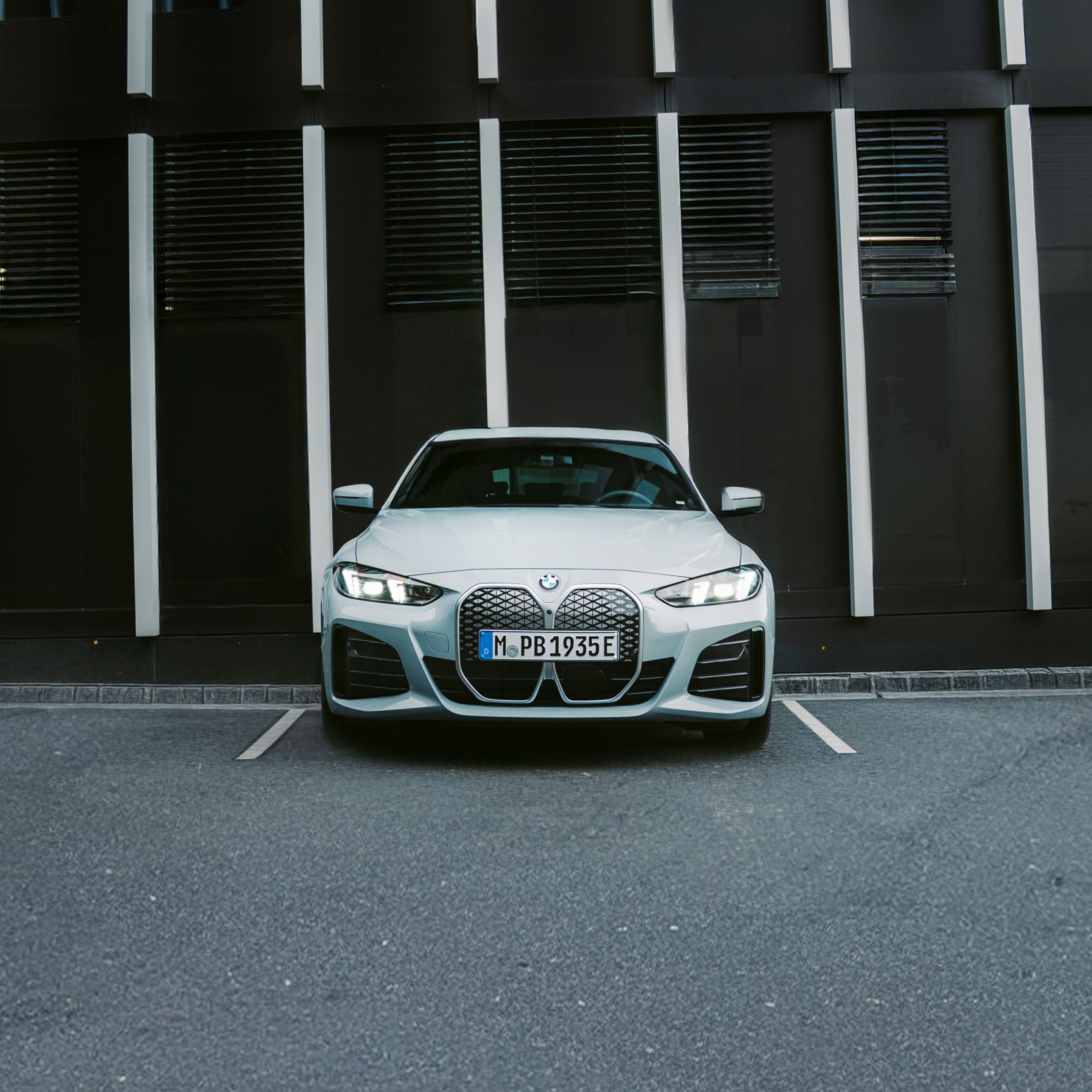 BMW i4 estacionado de frente num lugar de estacionamento em frente a um edifício.
