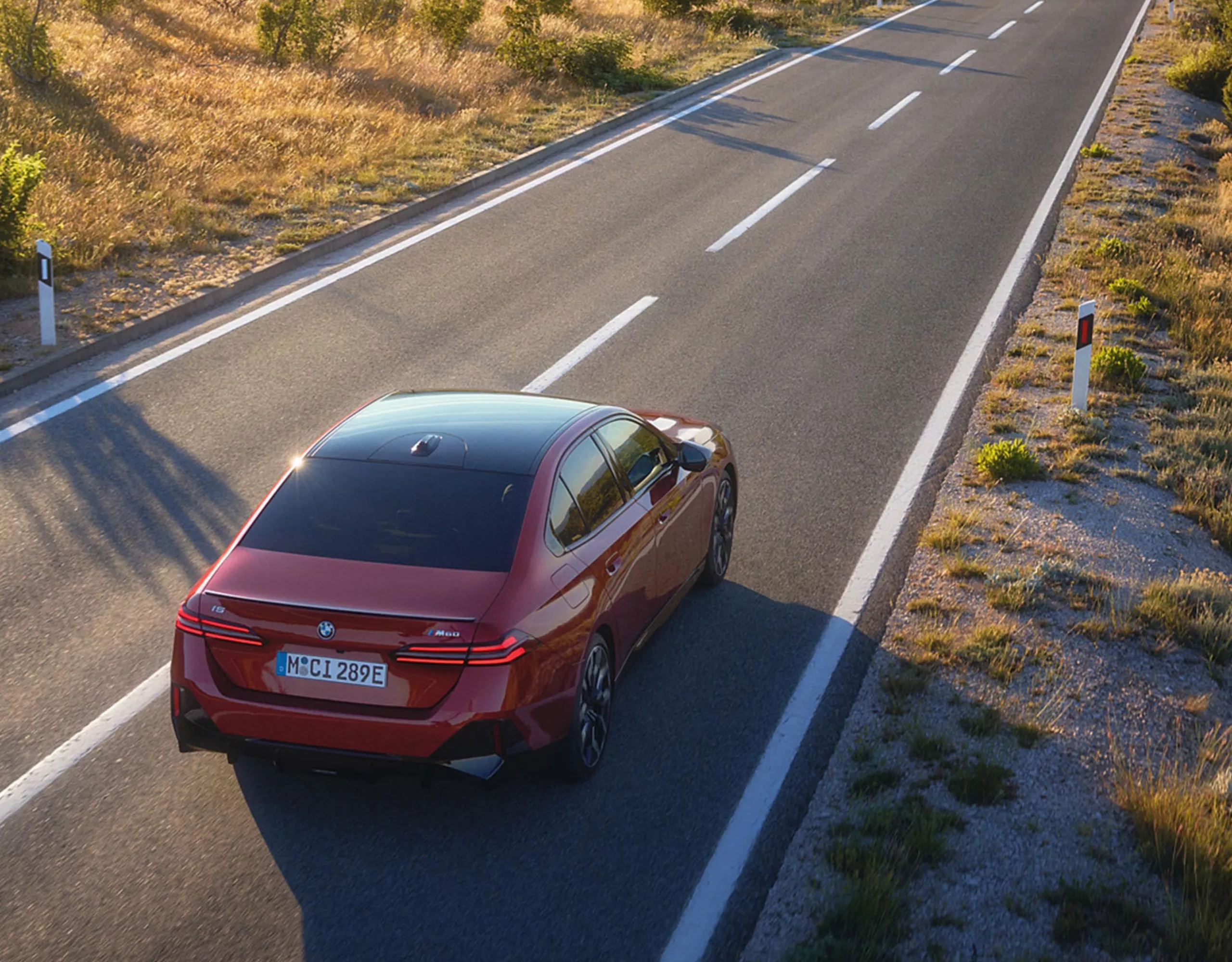 En röd BMW i5 som kör på en landsväg. 