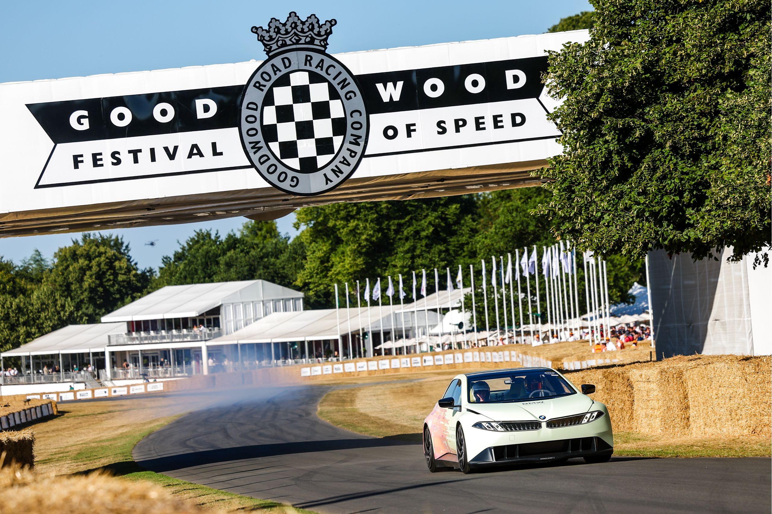 Ein roter sportlicher BMW fährt über eine Schotterstraße in einer grün bewachsenen Landschaft. 