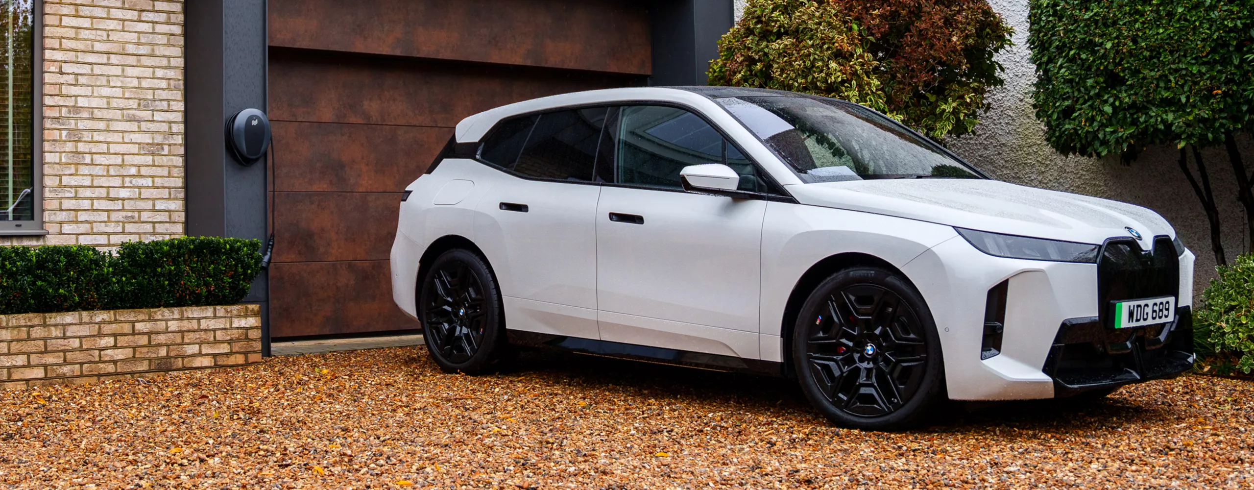 A woman is walking towards a BMW iX3 connected to a wallbox