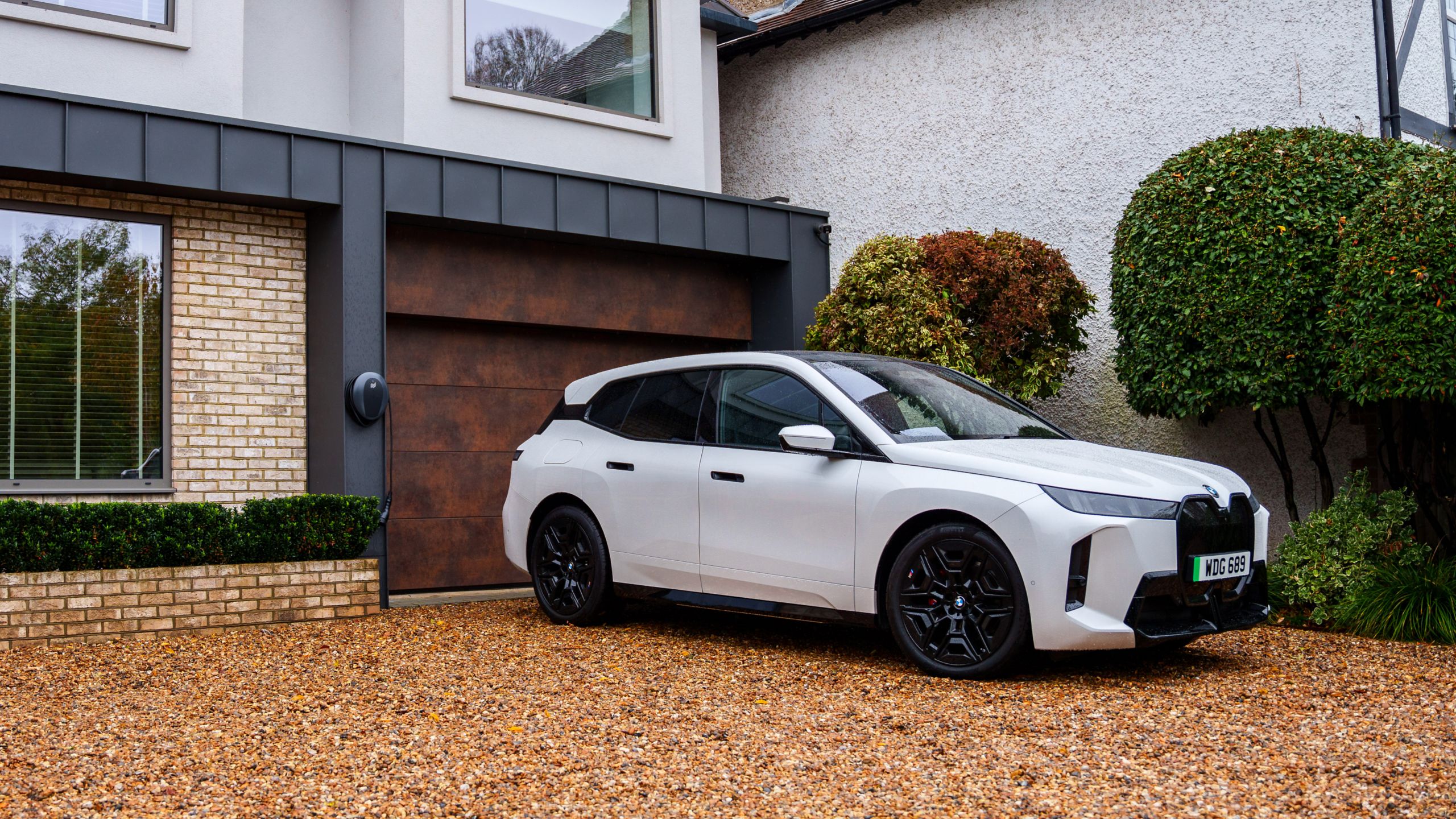 A woman is walking towards a BMW iX3 connected to a wallbox