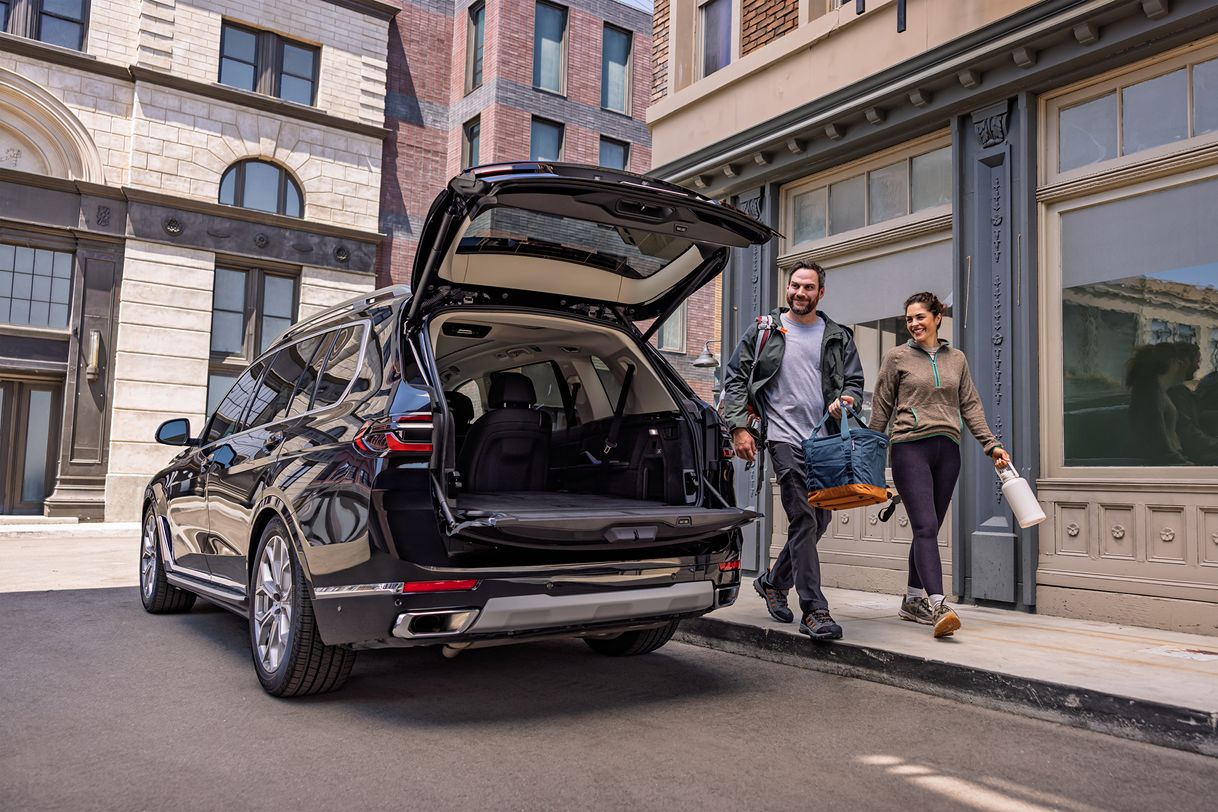 An athletic couple approaches their BMW with the tailgate open, ready to take off on a fun daytime excursion outside of the city.