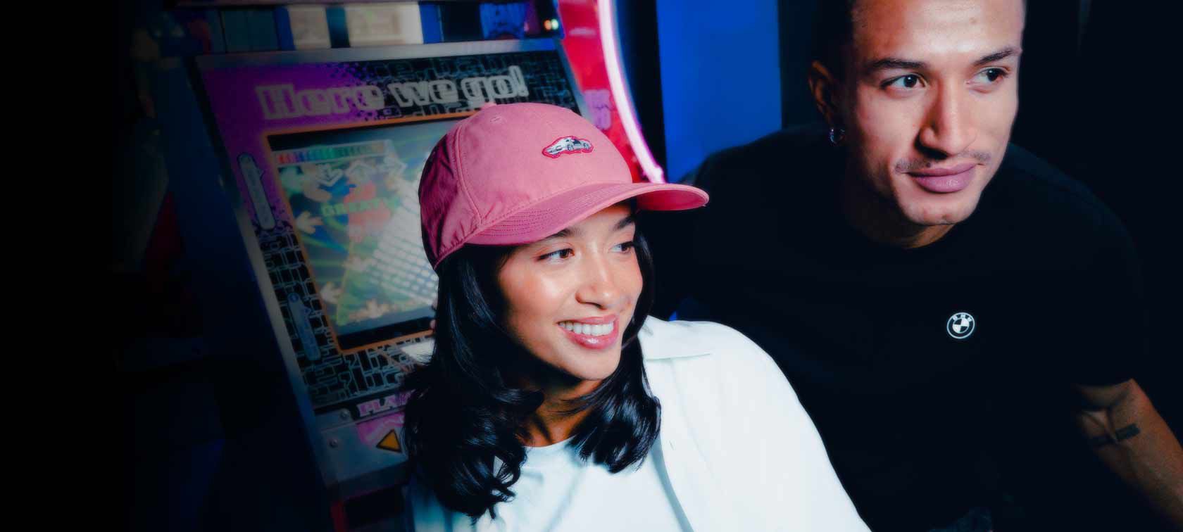 Gorra y camiseta de béisbol BMW Lifestyle que llevan puestas dos jóvenes en una sala de juegos