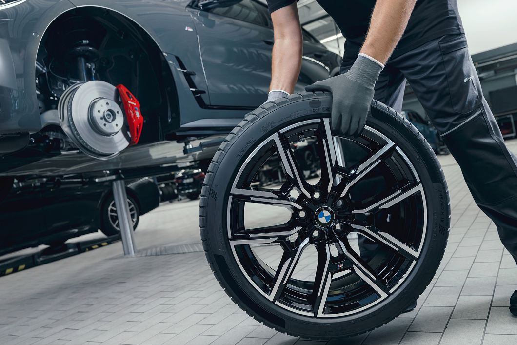 A close up of someone rolling a tire across a factory floor