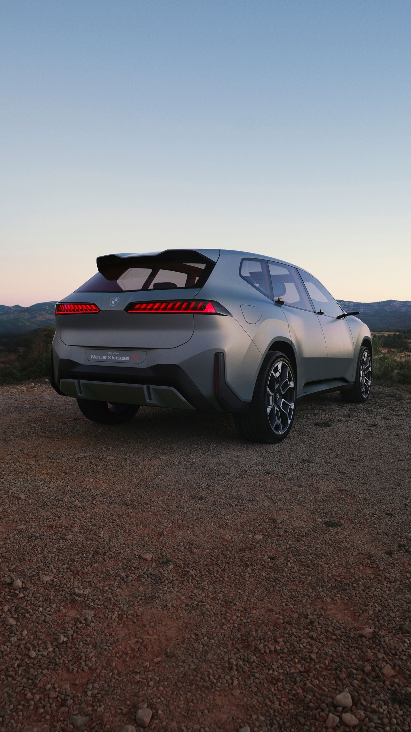 A rear shot of a BMW iX3 parked on a mountainous overlook.