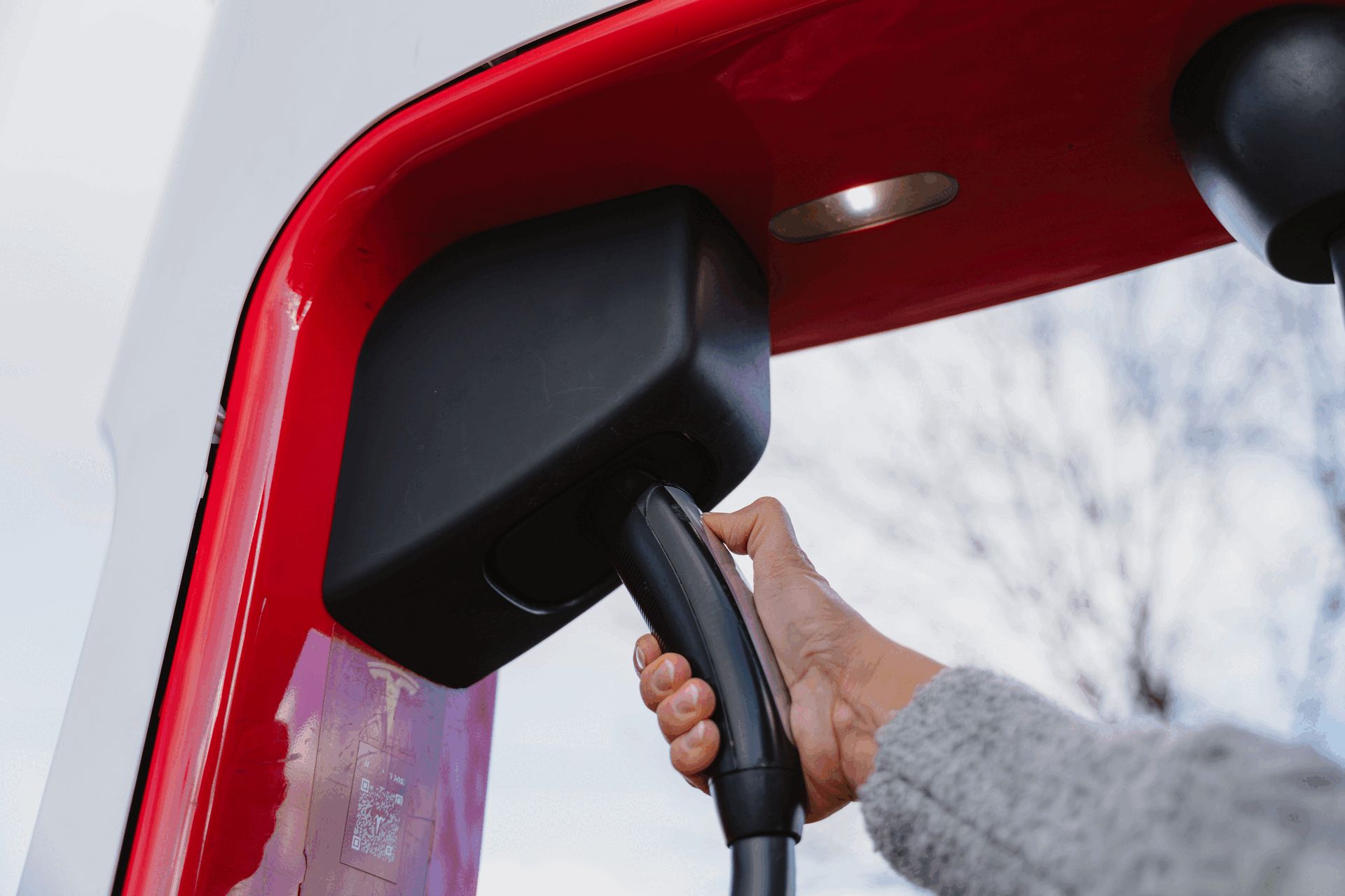 Close up of a hand grabbing a Magic Dock adapter at a Tesla Supercharger station