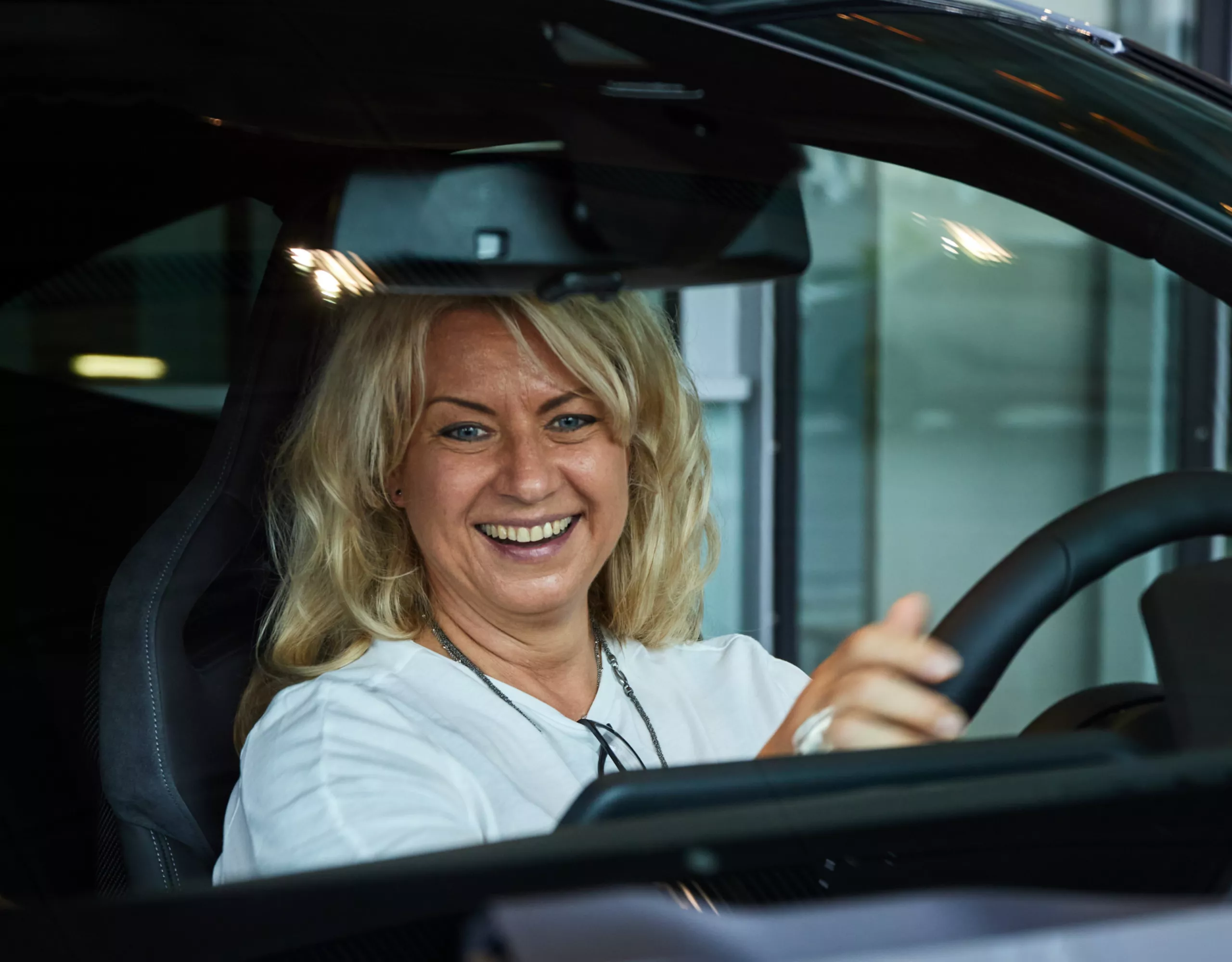 Happy woman sitting in her new BMW M4 at premium package pickup