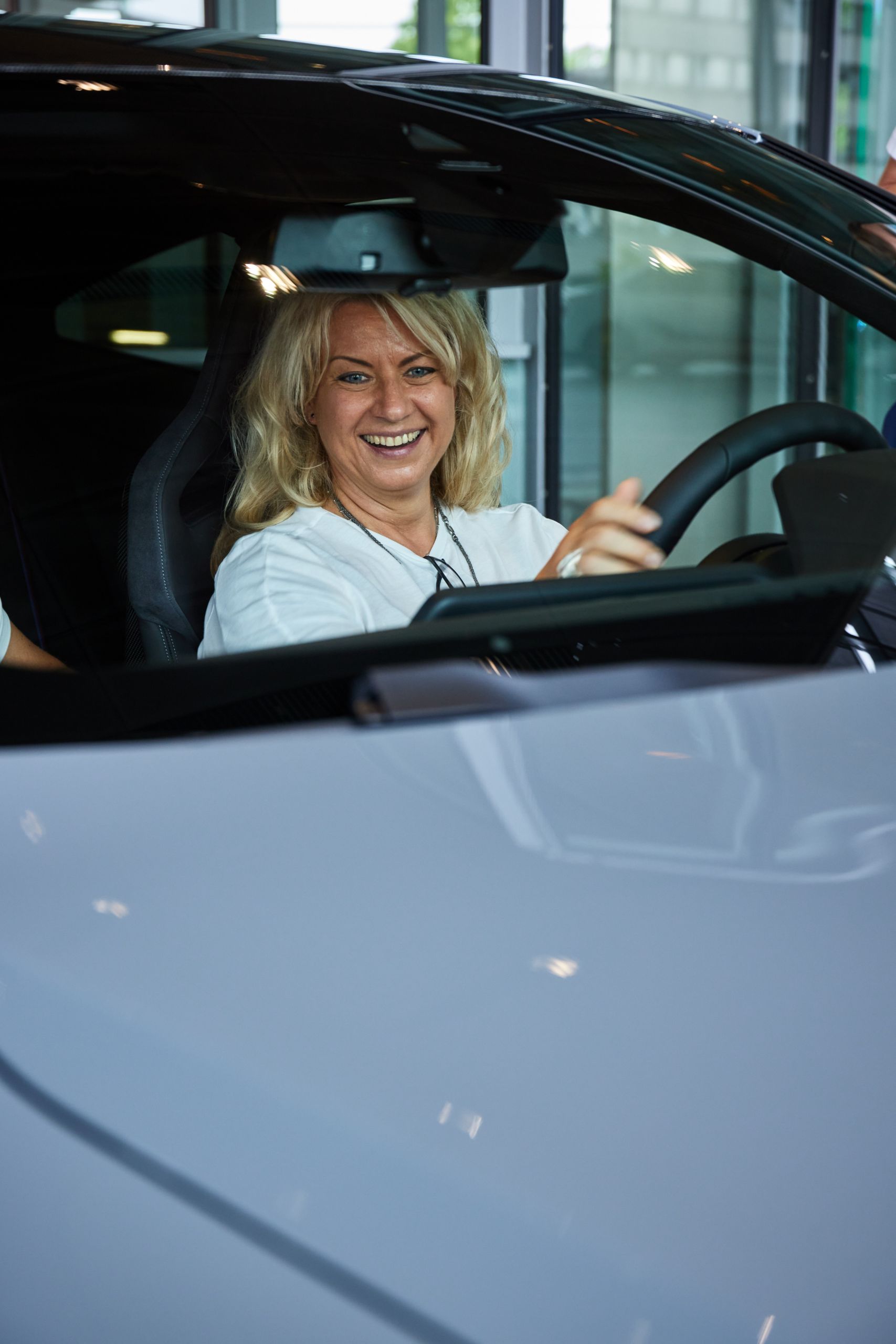Happy woman sitting in her new BMW M4 at premium package pickup