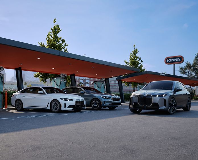 A BMW i4, i5, and iX parked at an IONNA charging station