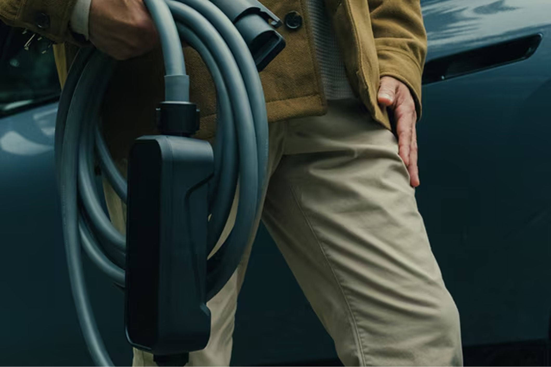 A hand holds a smartphone showcasing charging station locations on the My BMW App