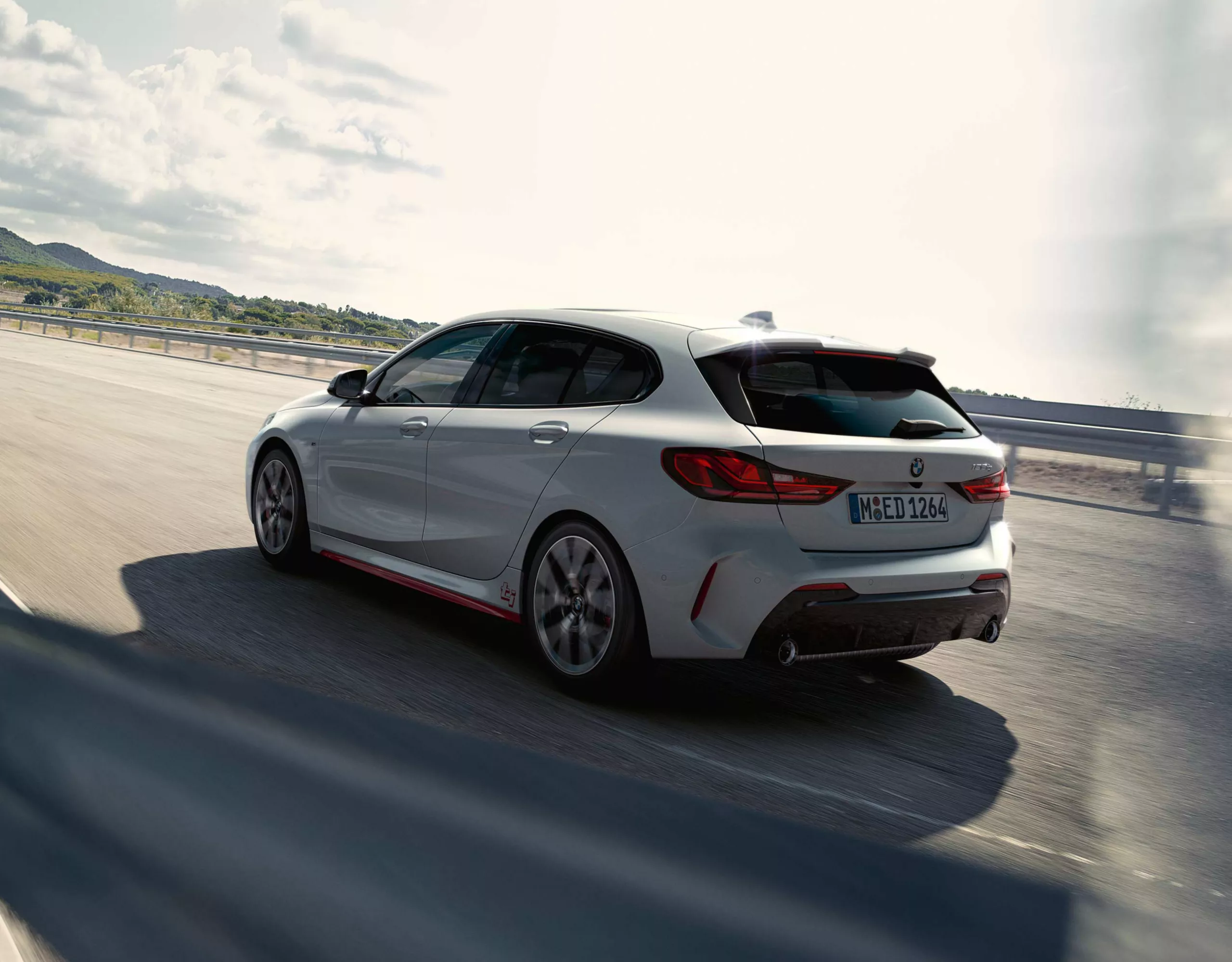 BMW Fahrzeug fährt entlang einer Landschaft mit Wasser im Hintergrund.