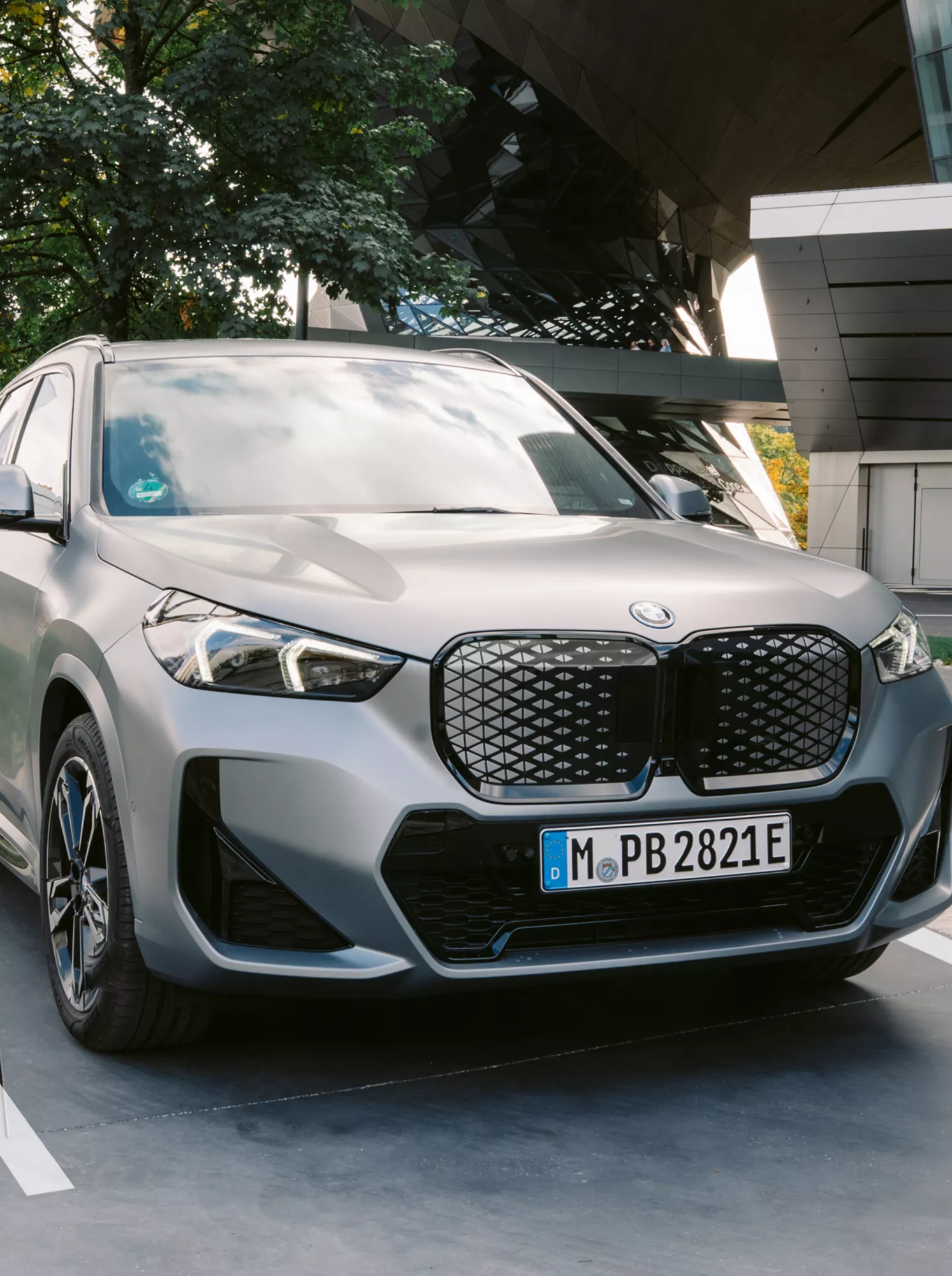 BMW iX1 Frontansicht unter modernem Holzvordach