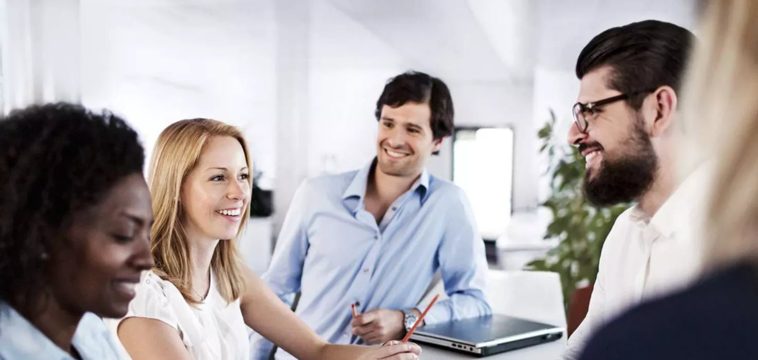 Bărbaţi şi femei stând în jurul unui birou şi discutând strategii