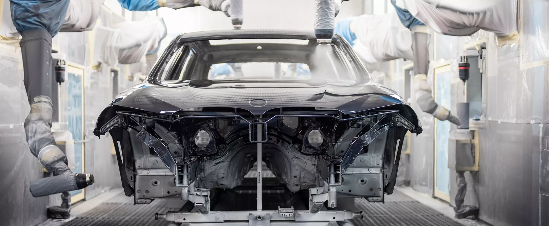 Automated machines apply a coating to the exterior of a semi-built BMW