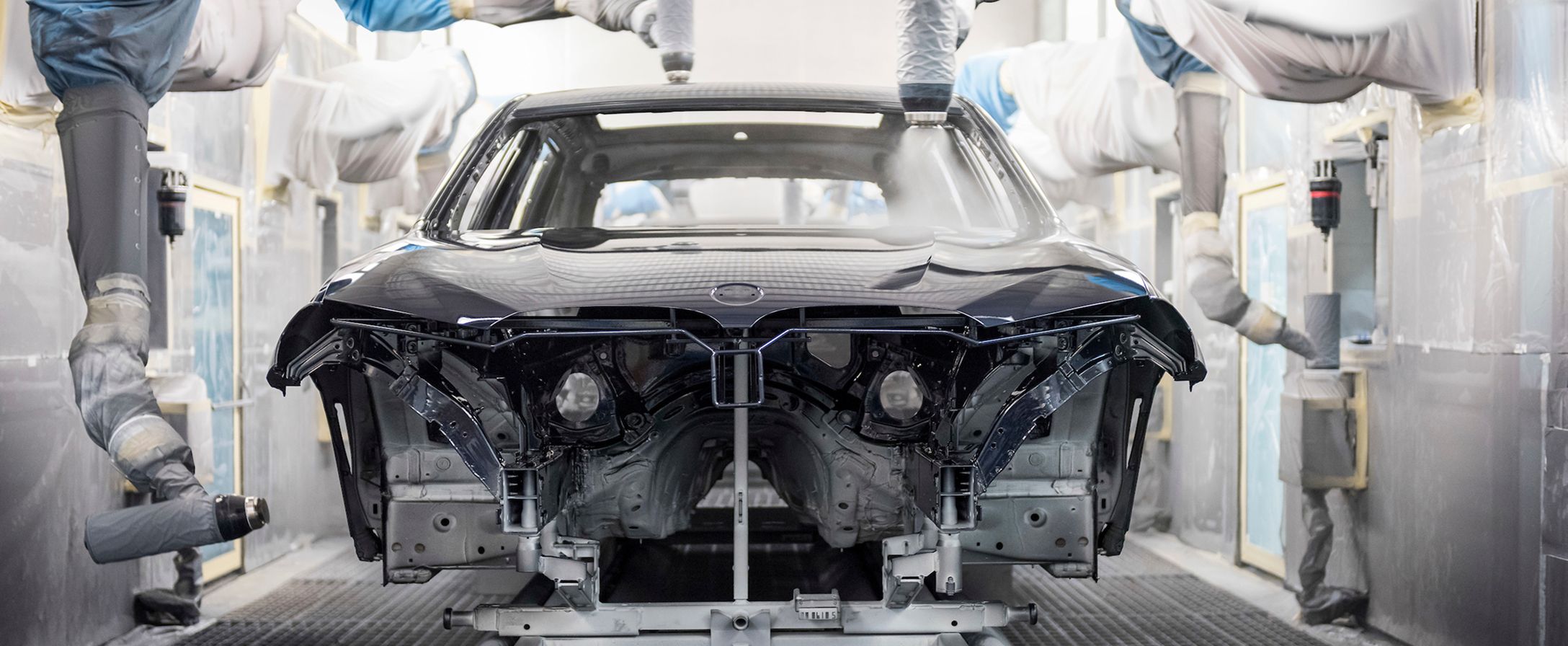 Automated machines apply a coating to the exterior of a semi-built BMW