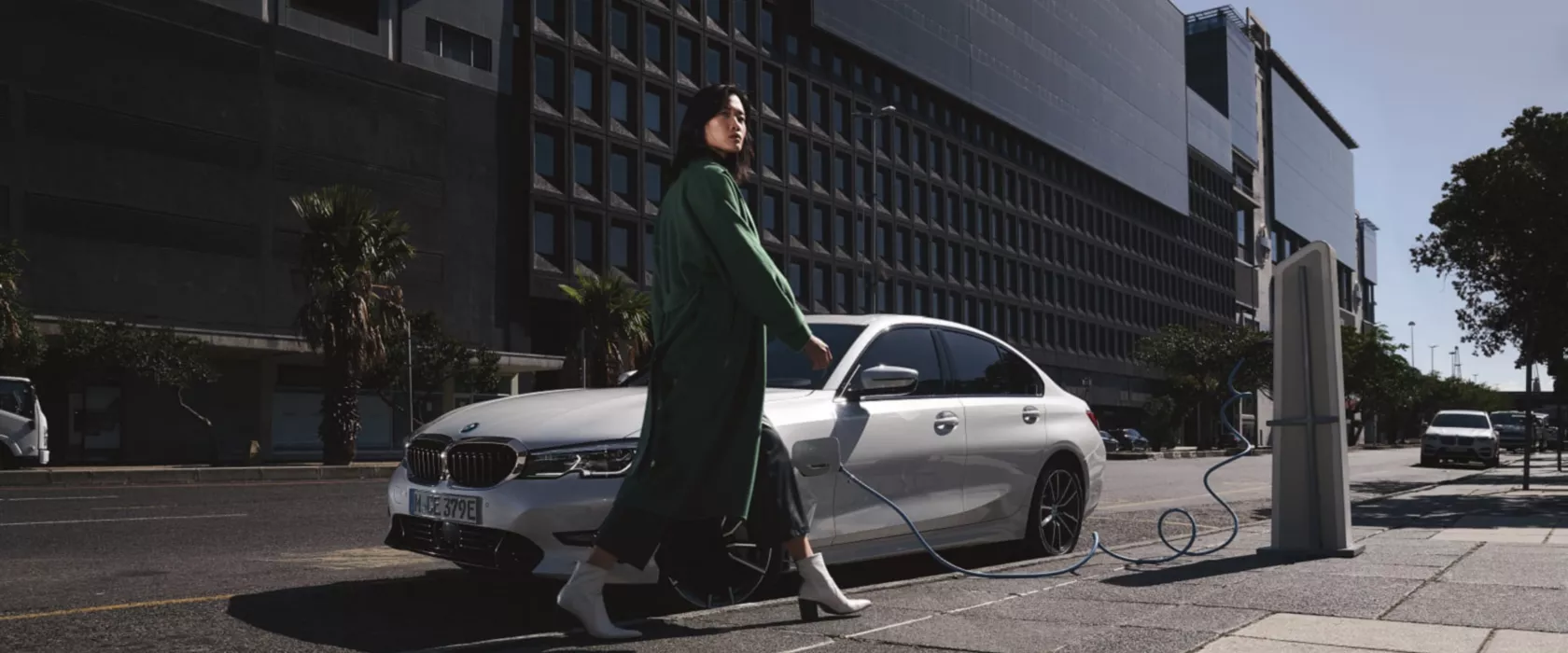 BMW Série 3 Berline d'occasion, blanche, garée et branchée à une borne de recharge