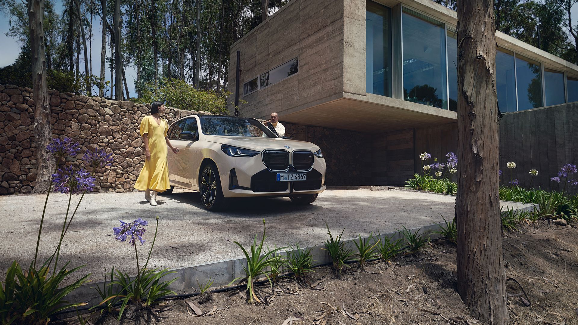 Eine Frau und ein Mann stehen neben einem beigen BMW X3.