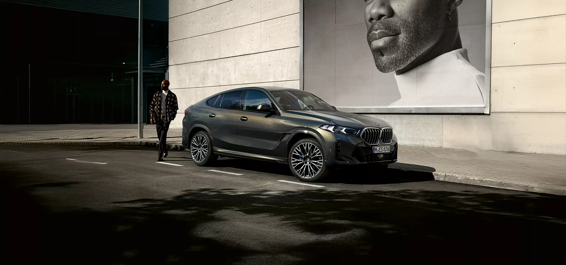 Ein Mann steht neben einem geparkten BMW X6