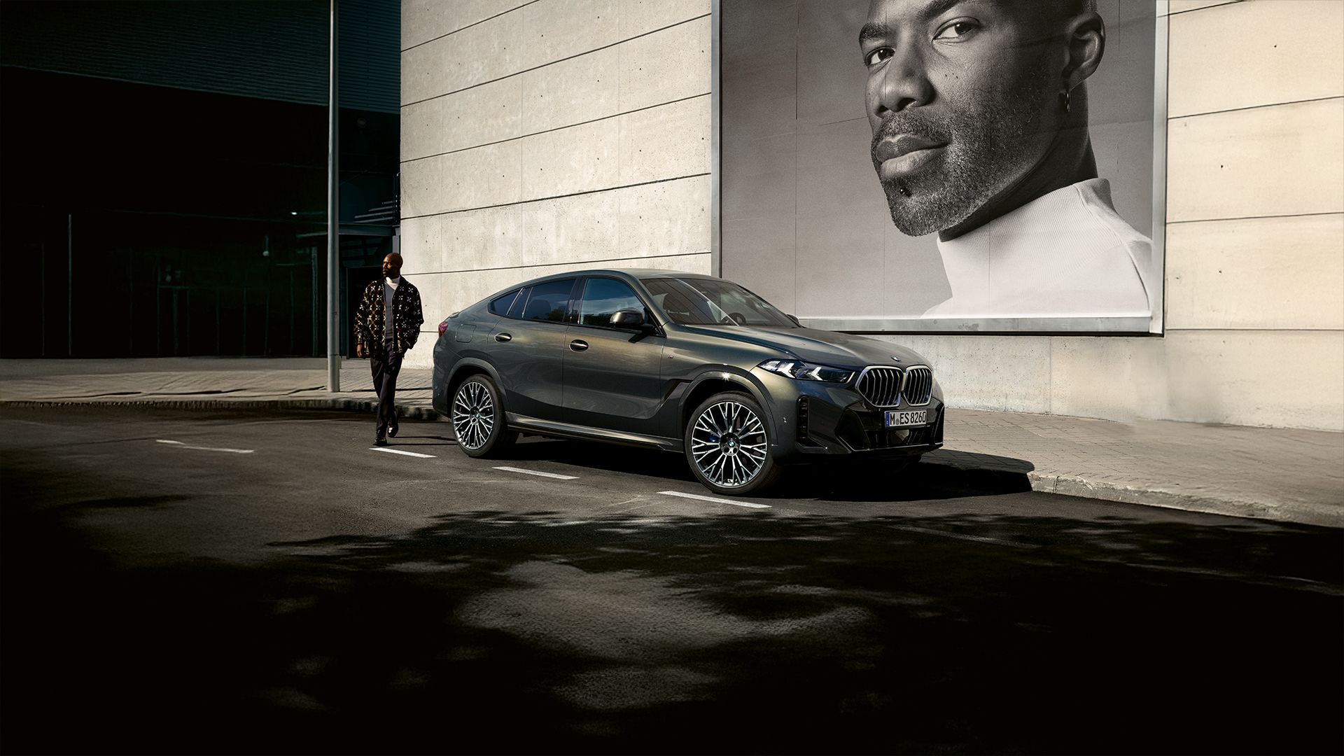 Ein Mann steht neben einem geparkten BMW X6