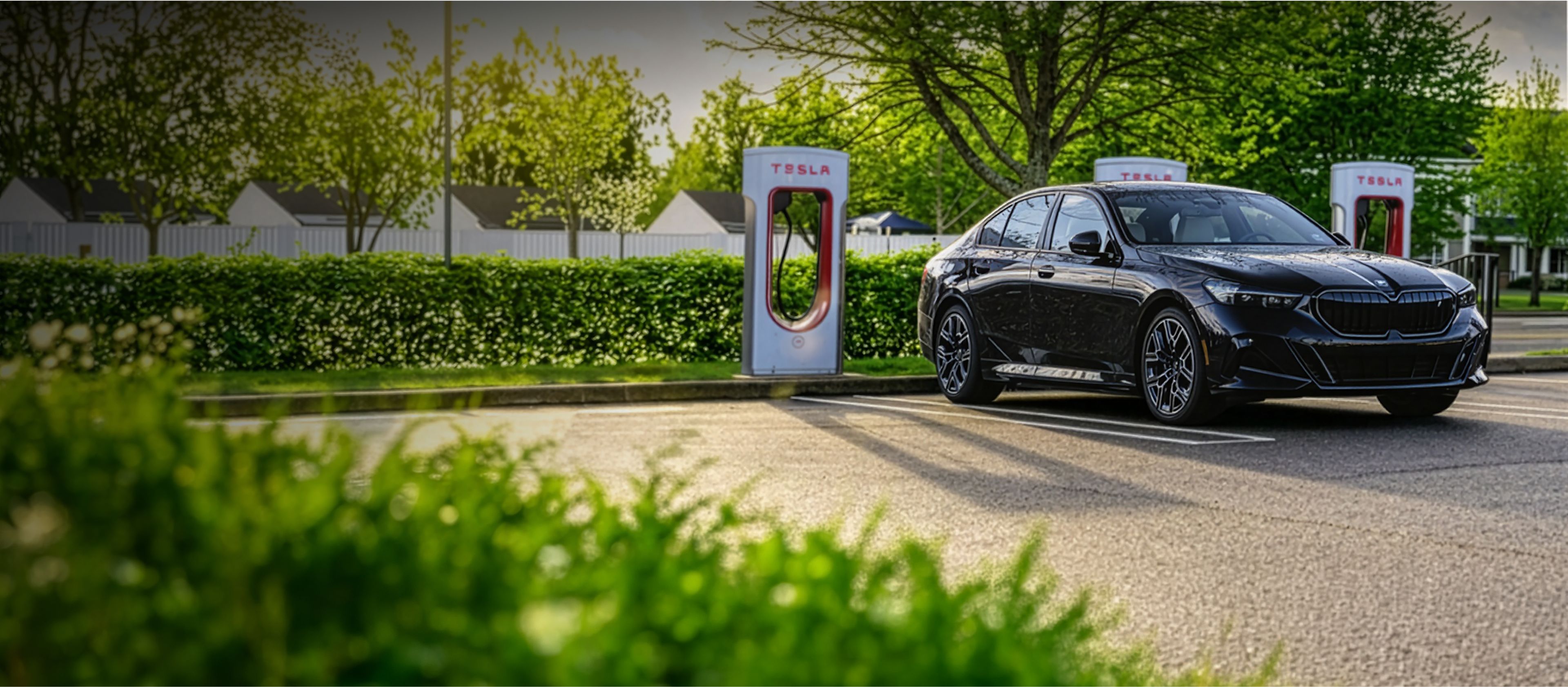 A BMW i5 sedan charges at a Tesla Supercharger station