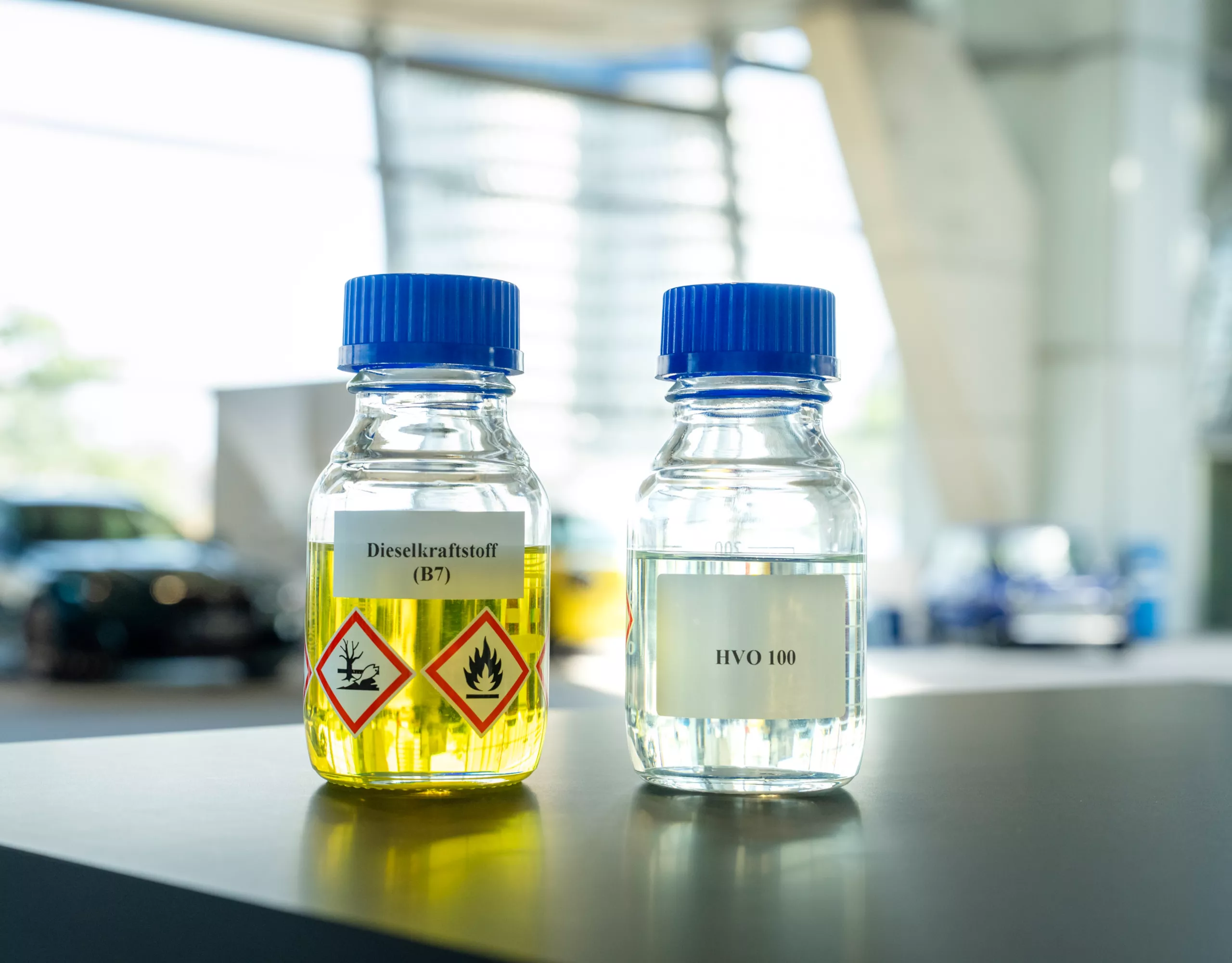 Zwei Laborflaschen, in denen herkömmlicher B7-Diesel und erneuerbarer HVO100-Diesel nebeneinander präsentiert werden